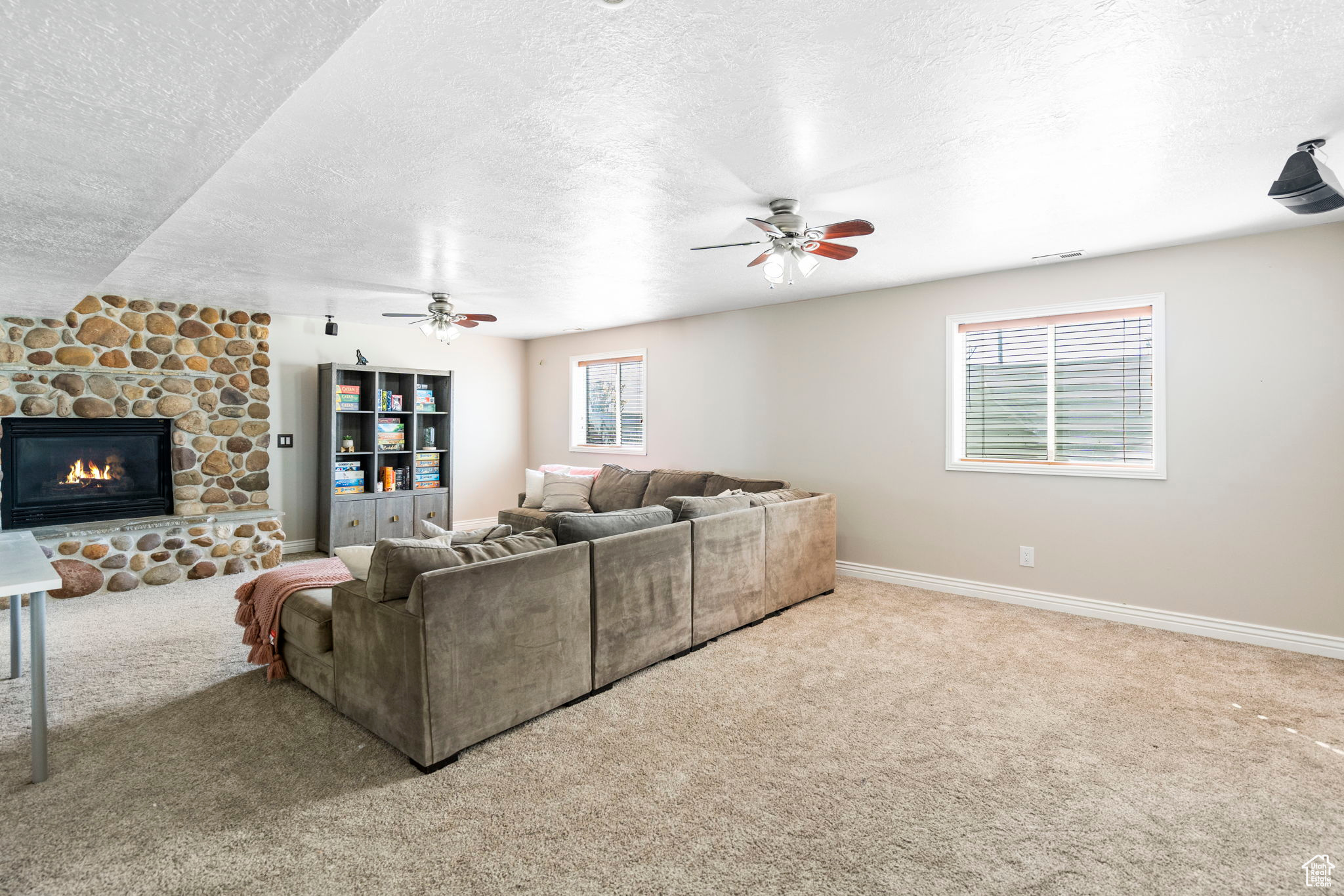 Living room with carpet, ceiling fan, a textured ceiling, and a fireplace