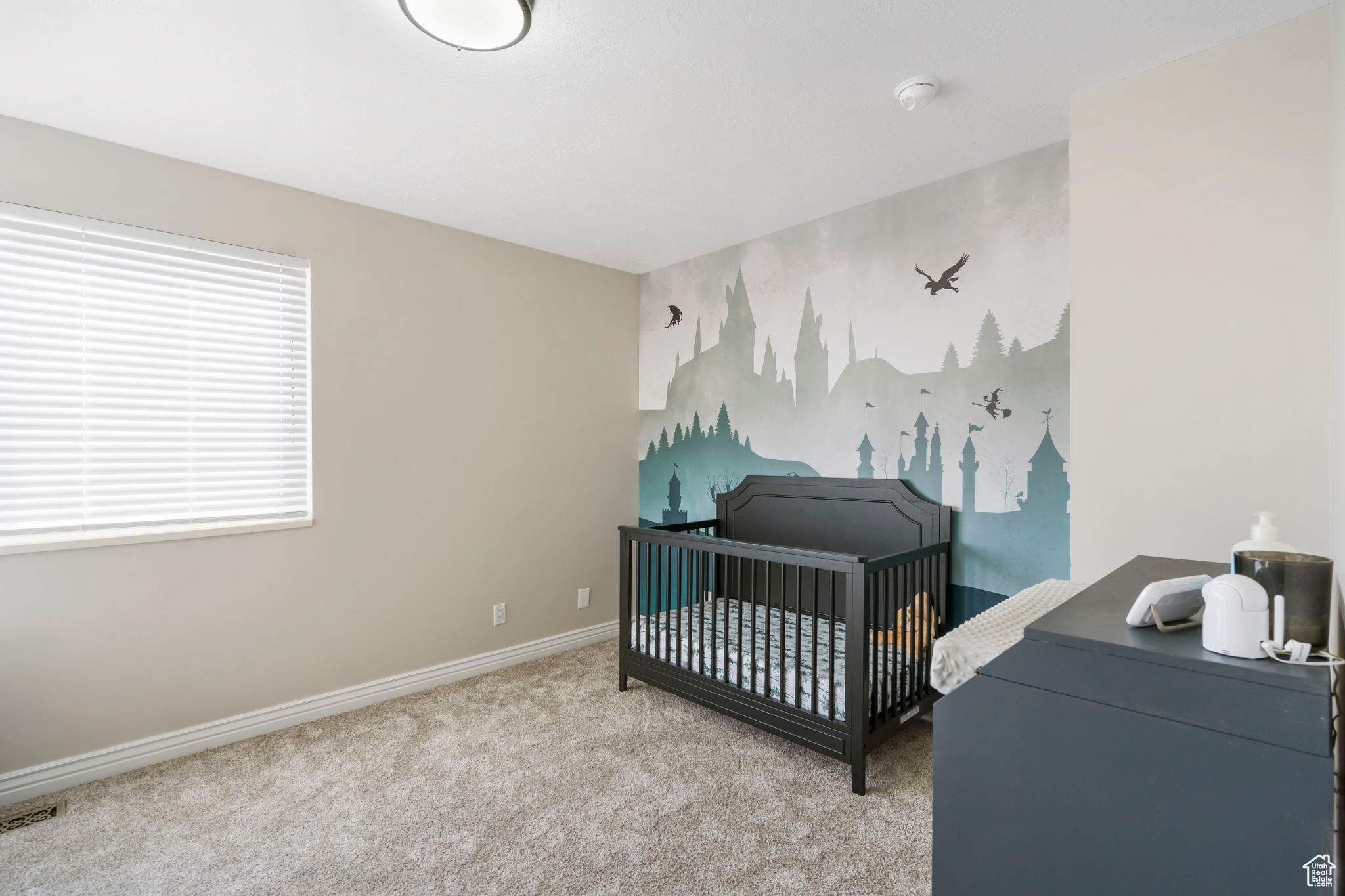 Bedroom featuring light carpet and a crib