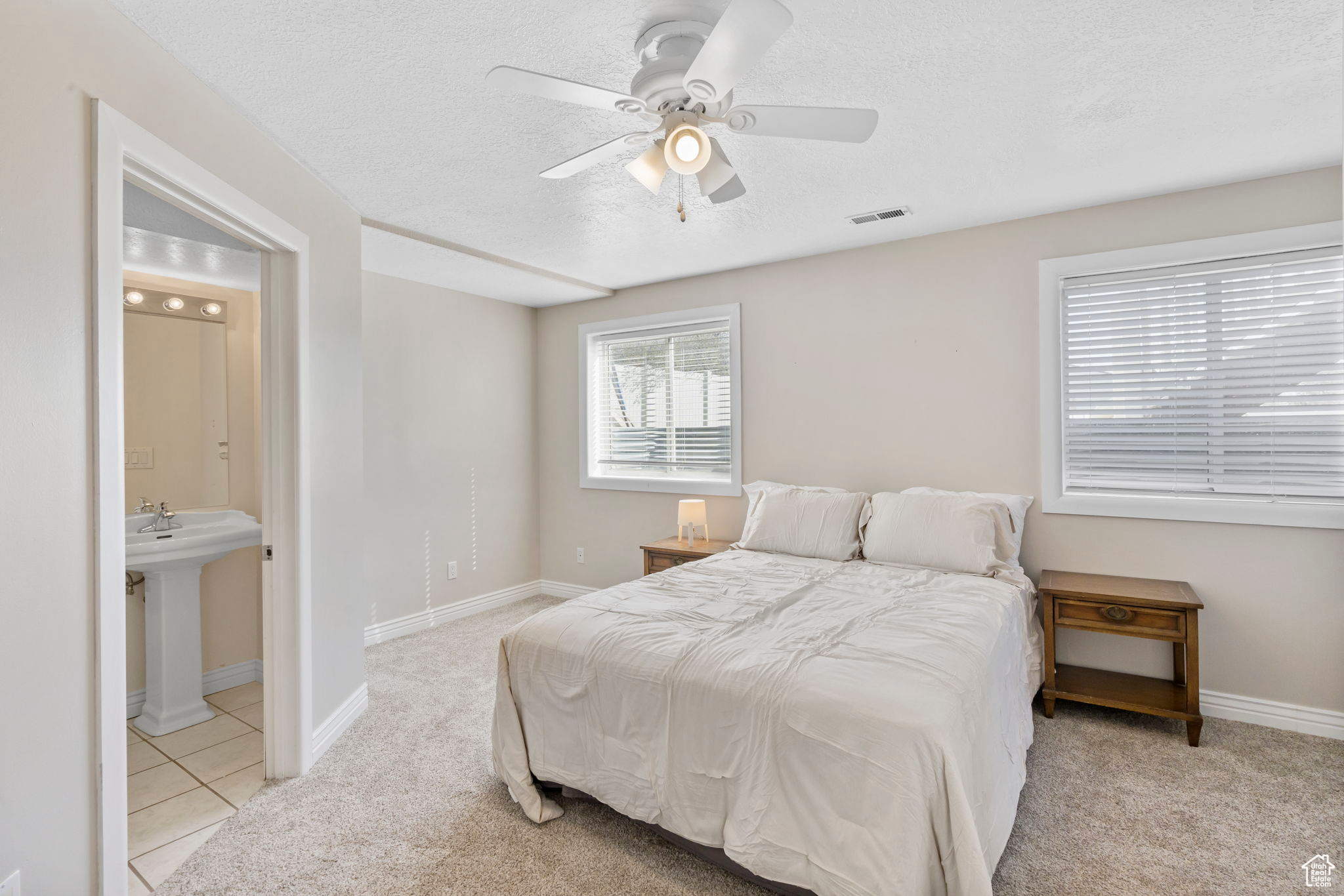 Bedroom with light colored carpet, a textured ceiling, ceiling fan, and ensuite bathroom