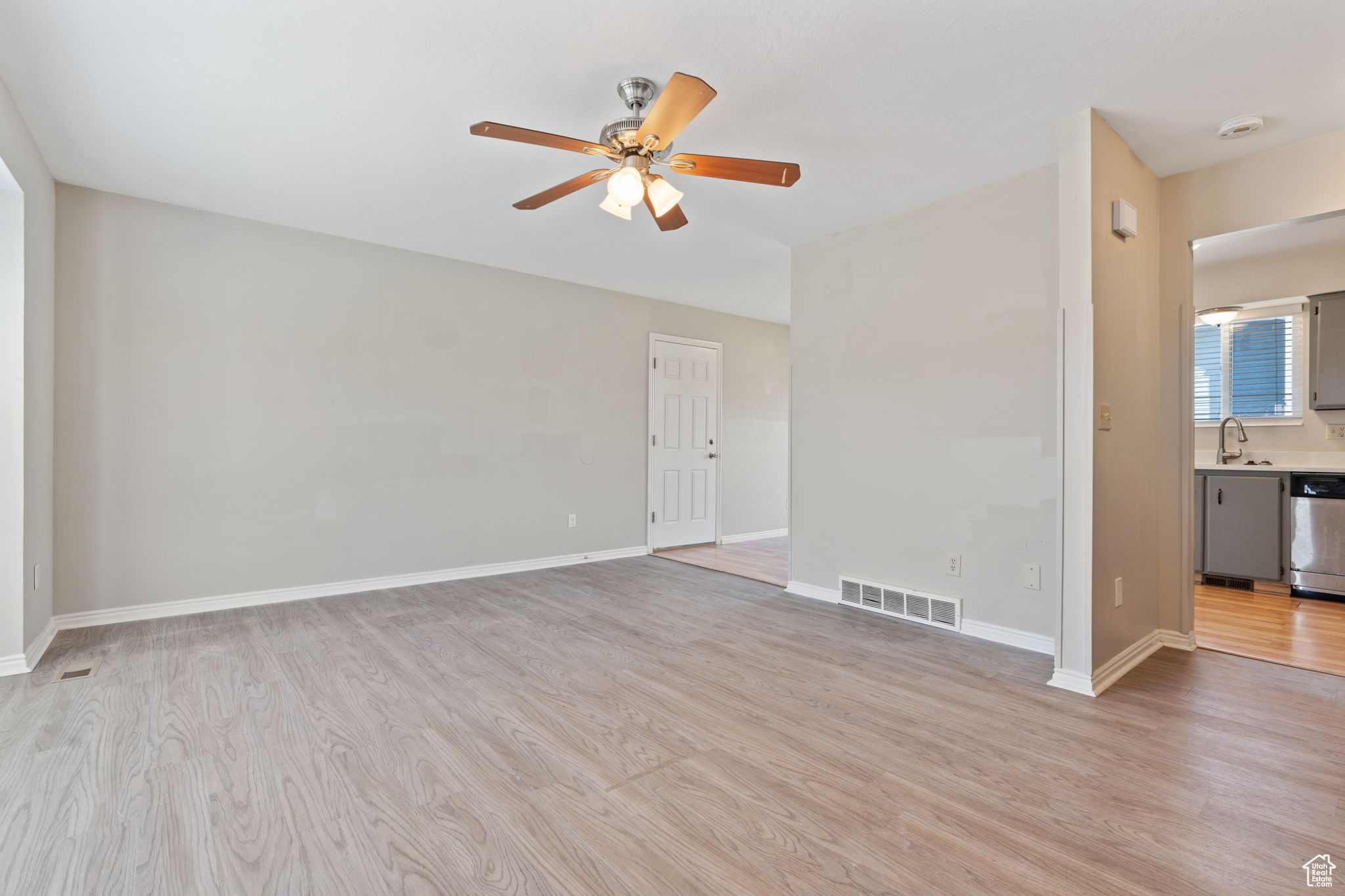Empty room with light hardwood / wood-style flooring, ceiling fan, and sink