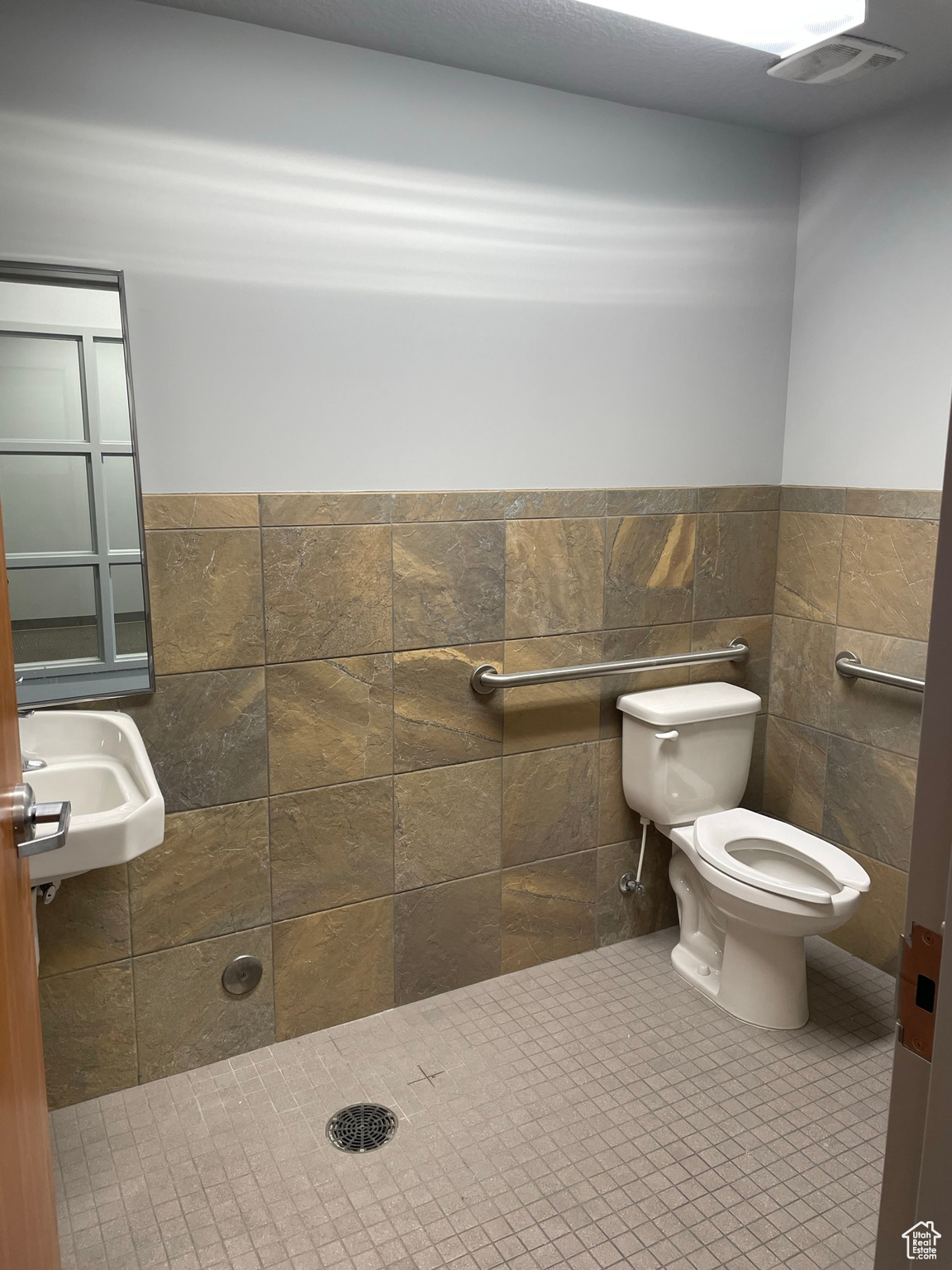 Bathroom with tile floors, a shower, tile walls, and toilet