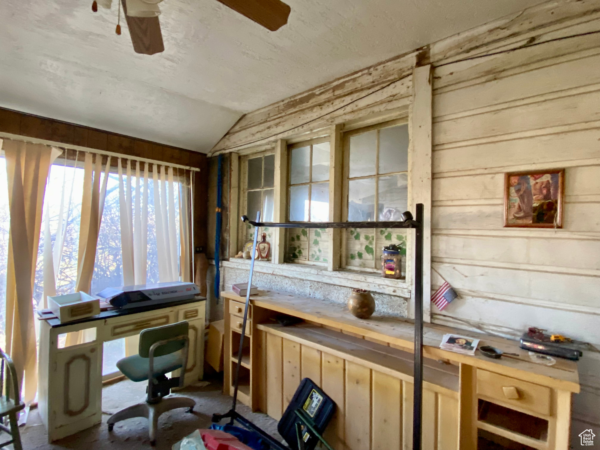 Office space with lofted ceiling, wood walls, and ceiling fan