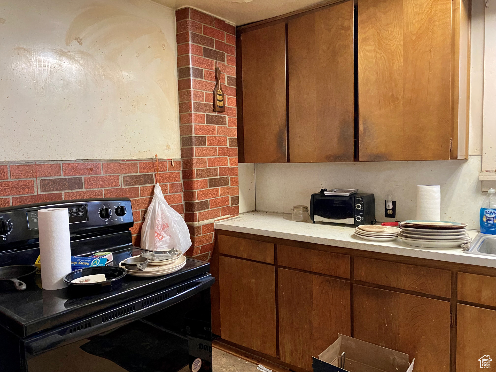 Kitchen featuring brick wall and black range with electric cooktop