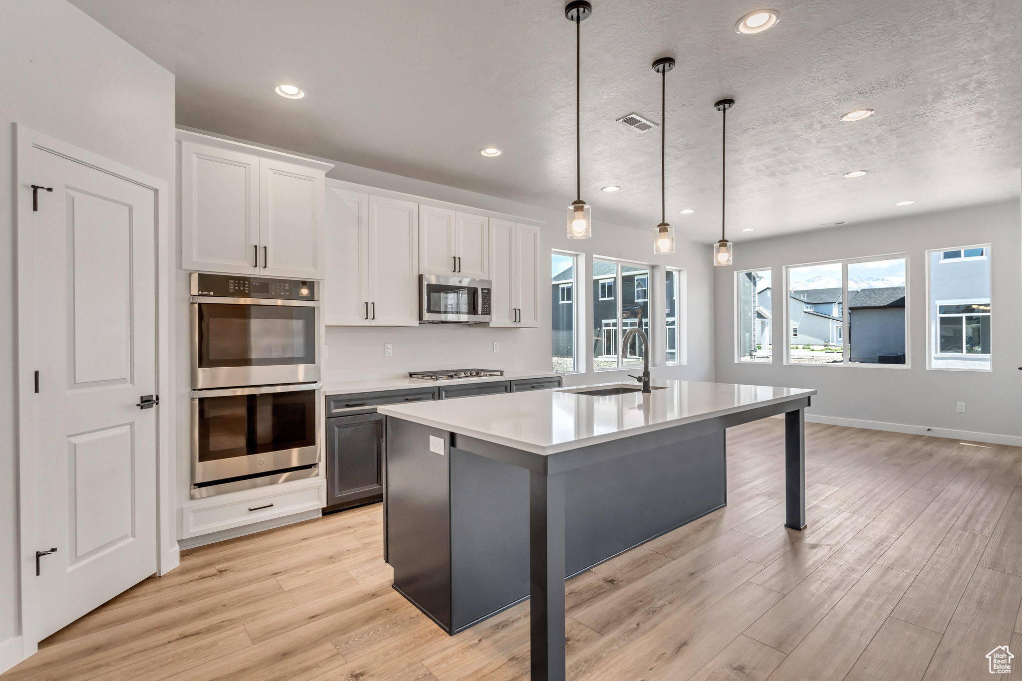 PHOTOS FROM A SIMILAR HOME. COLORS AND SELECTIONS WILL VARY.  Kitchen with white cabinets, sink, stainless steel appliances, and decorative light fixtures