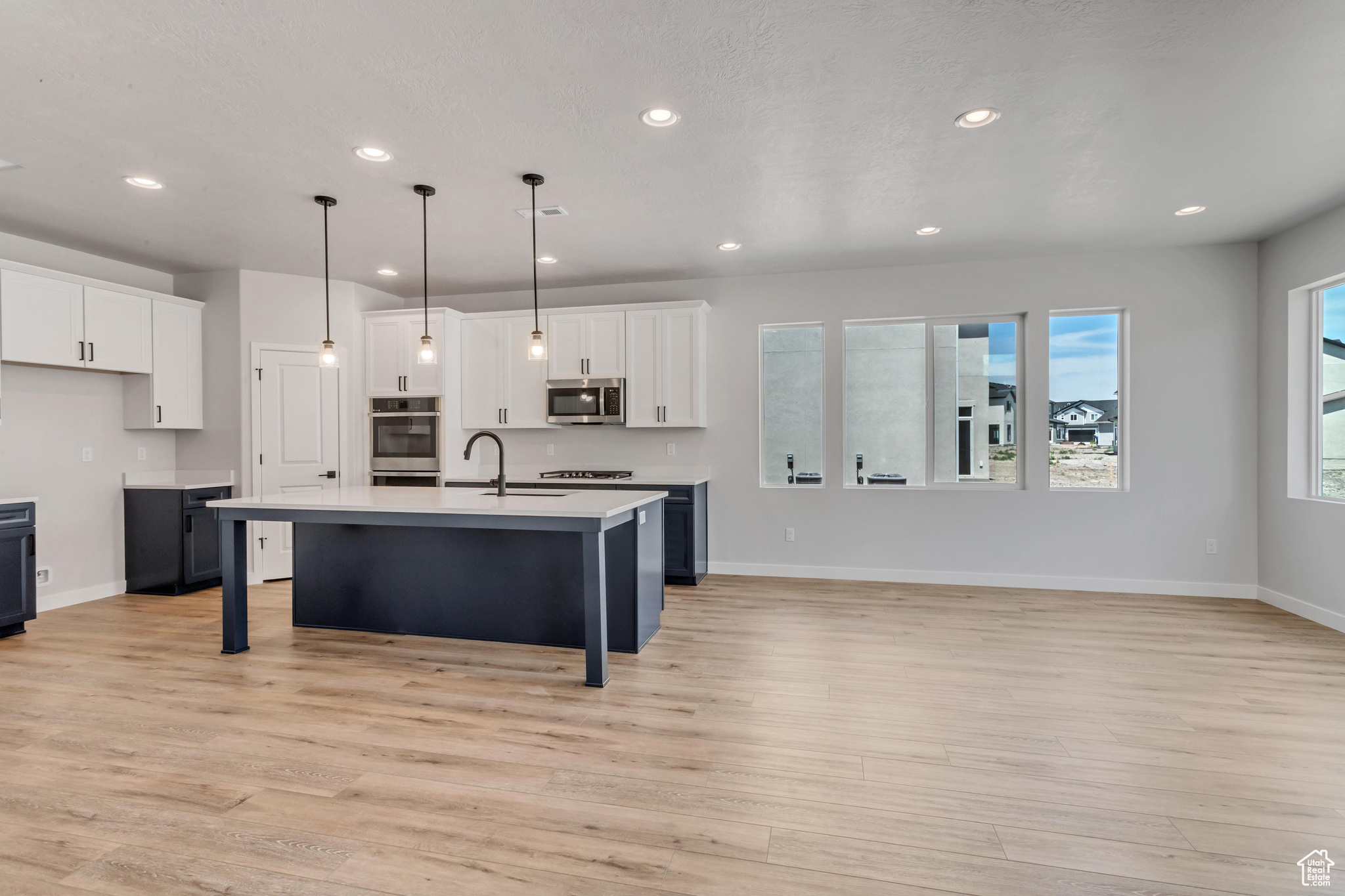 PHOTOS FROM A SIMILAR HOME. COLORS AND SELECTIONS WILL VARY.  Kitchen with light hardwood / wood-style floors, stainless steel appliances, and a kitchen island with sink