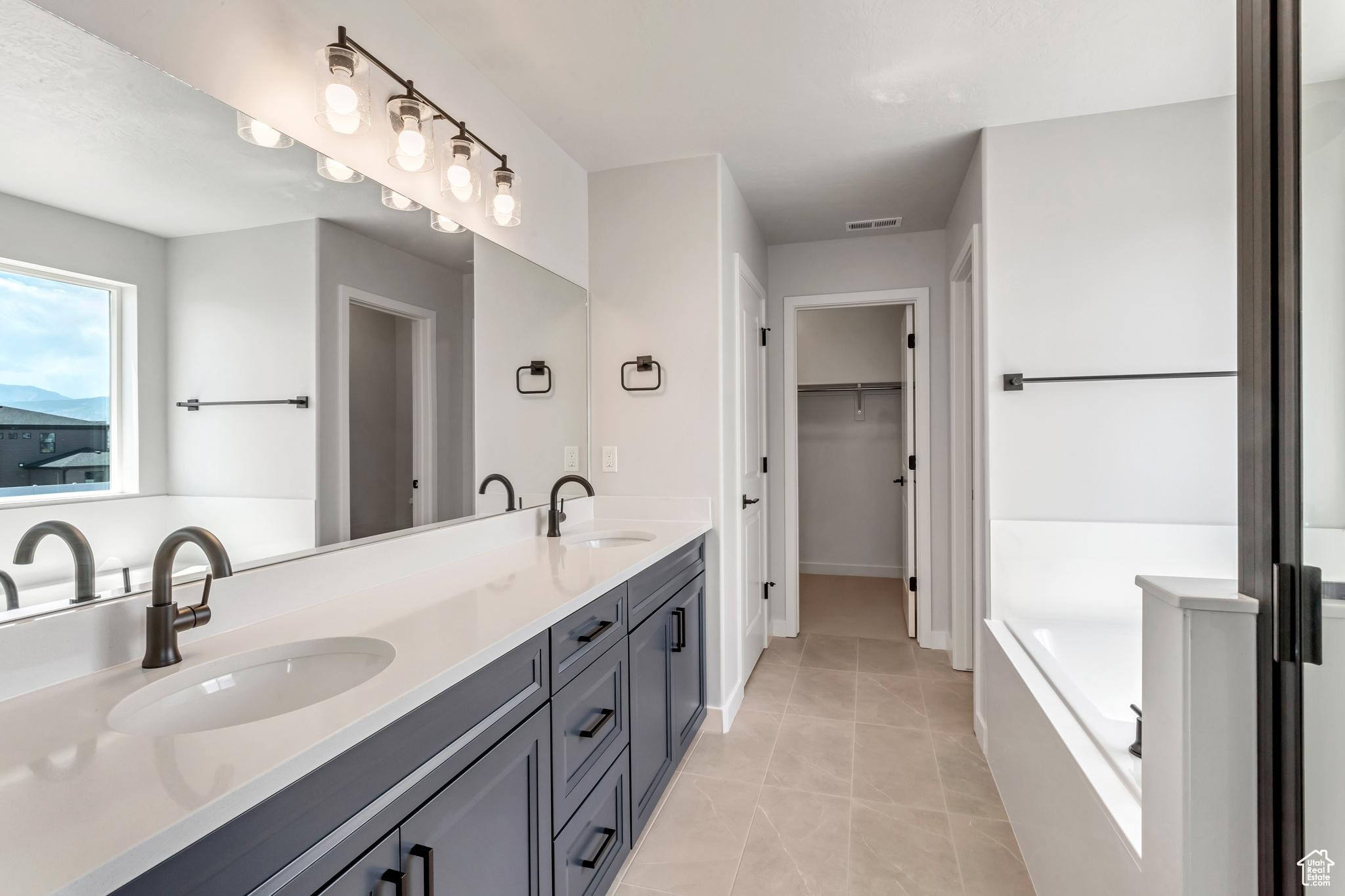 PHOTOS FROM A SIMILAR HOME. COLORS AND SELECTIONS WILL VARY.  Primary Suite Bathroom featuring tile flooring, a tub, vanity with extensive cabinet space, and dual sinks