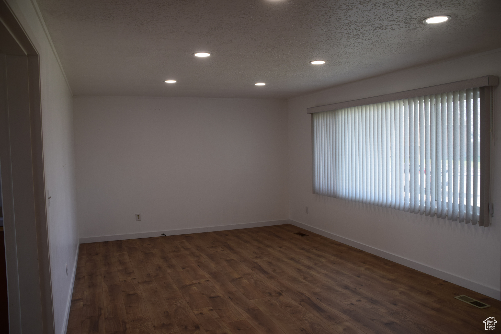 Empty room featuring a wealth of natural light, dark hardwood / wood-style floors, and a textured ceiling