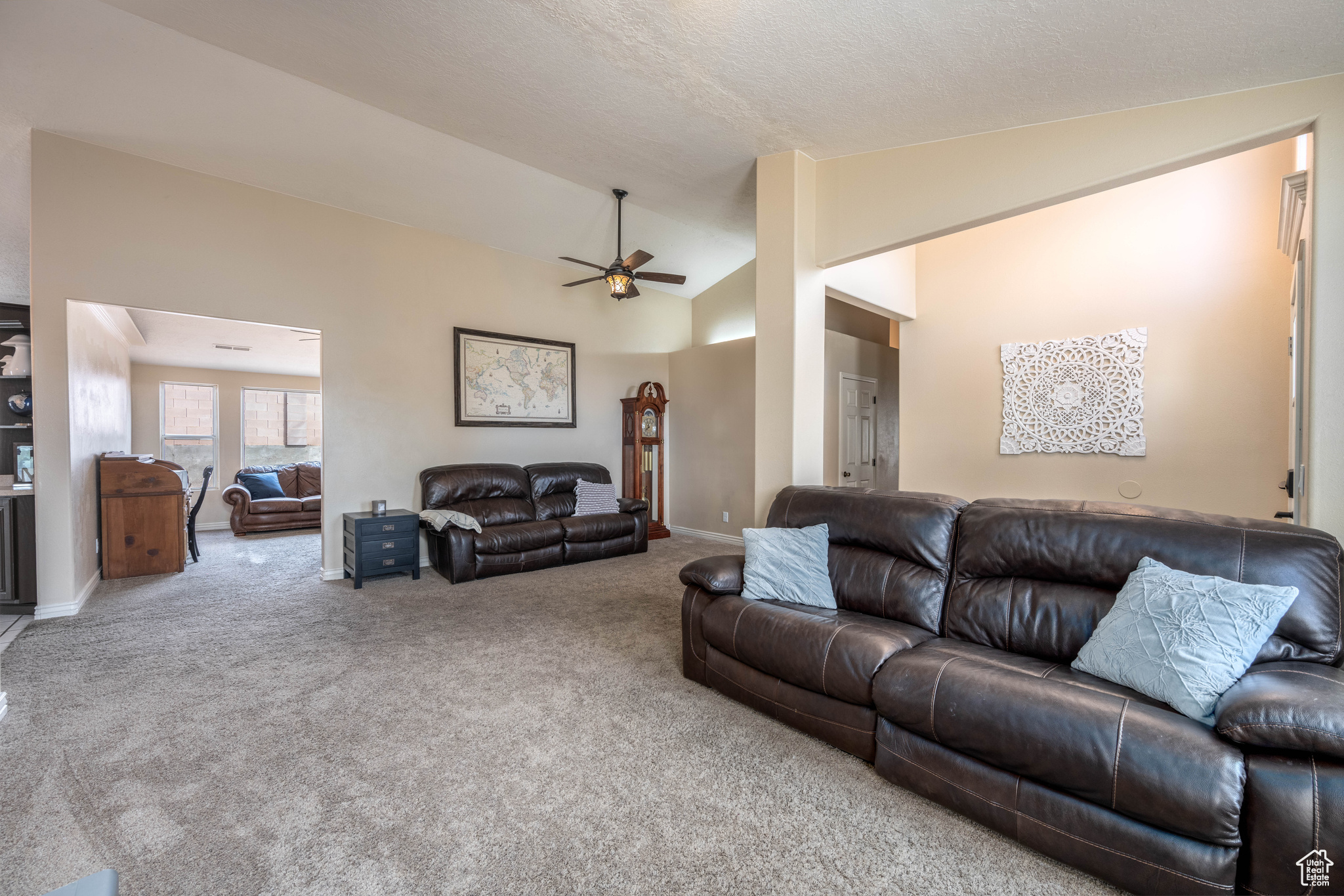 Living room featuring lofted ceiling, ceiling fan, light carpet, and a textured ceiling