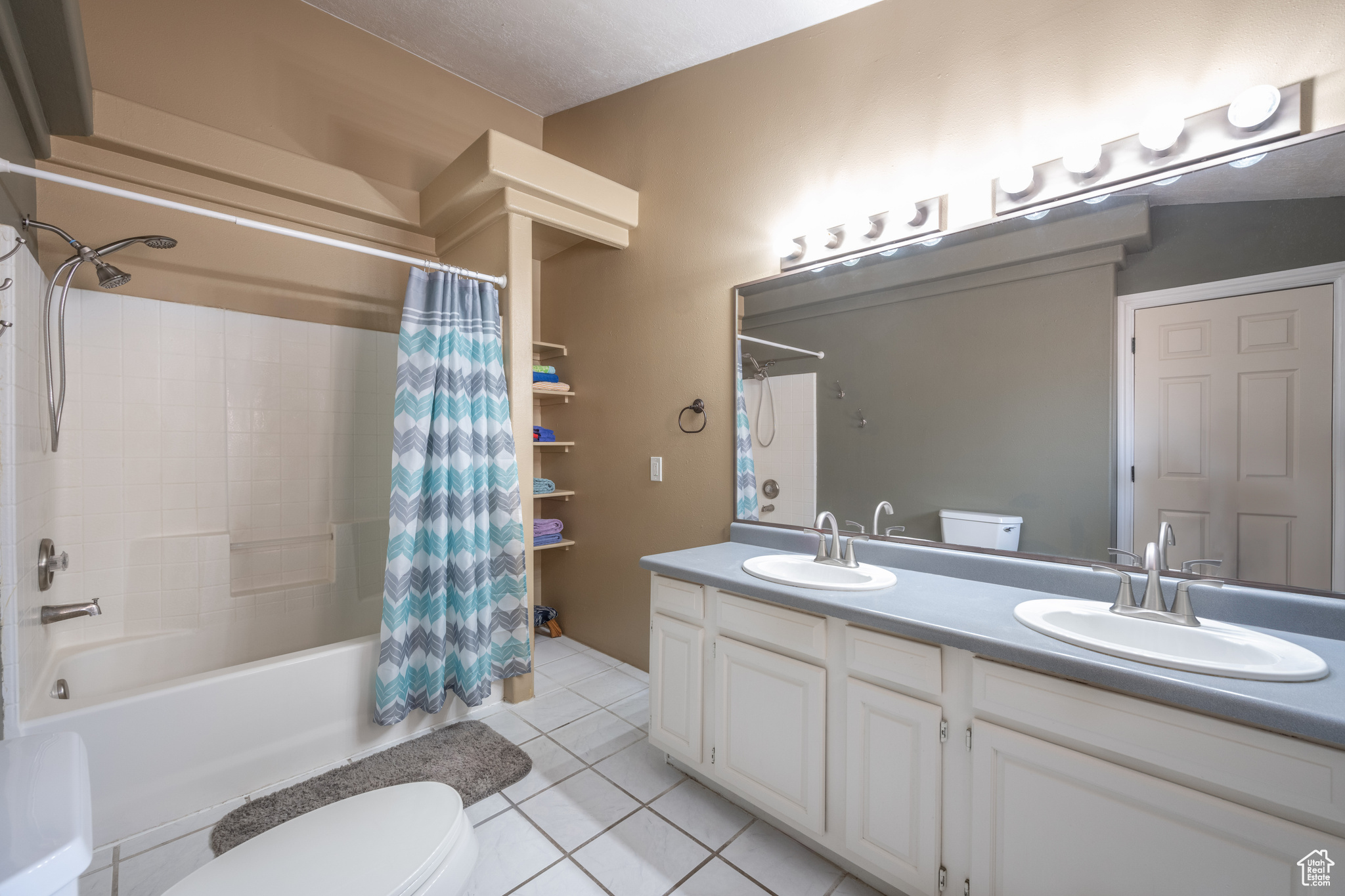 Full bathroom featuring tile floors, shower / bathtub combination with curtain, toilet, and double sink vanity
