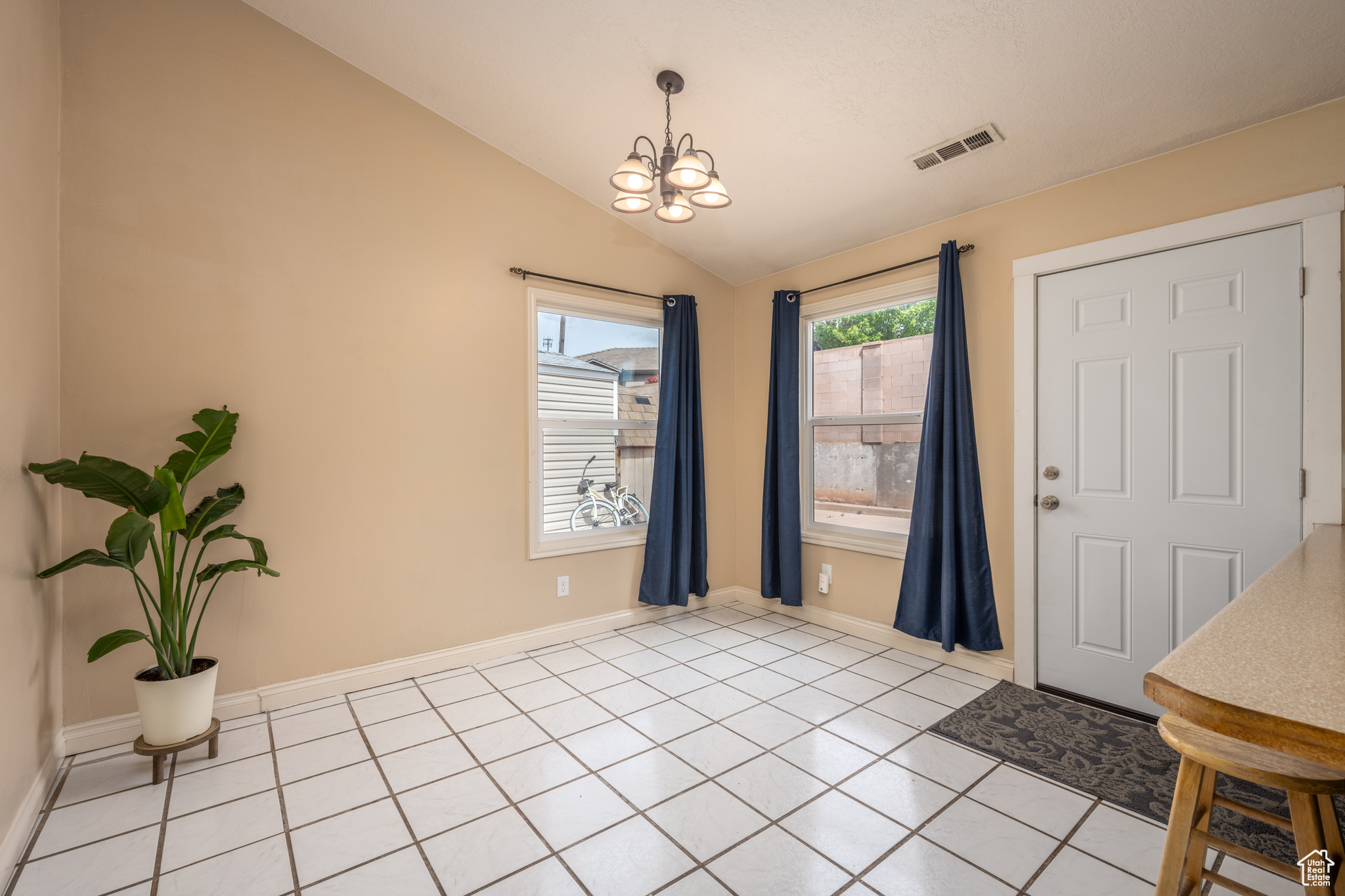 Entrance foyer featuring vaulted ceiling, an inviting chandelier, and light tile floors