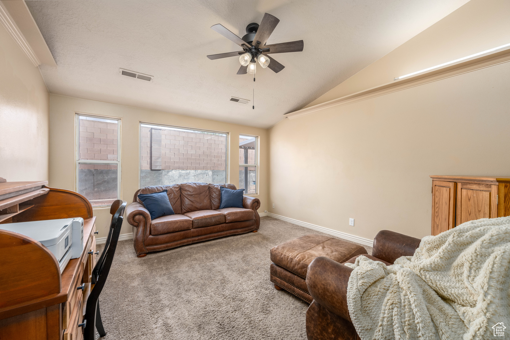 Carpeted living room featuring ceiling fan and vaulted ceiling