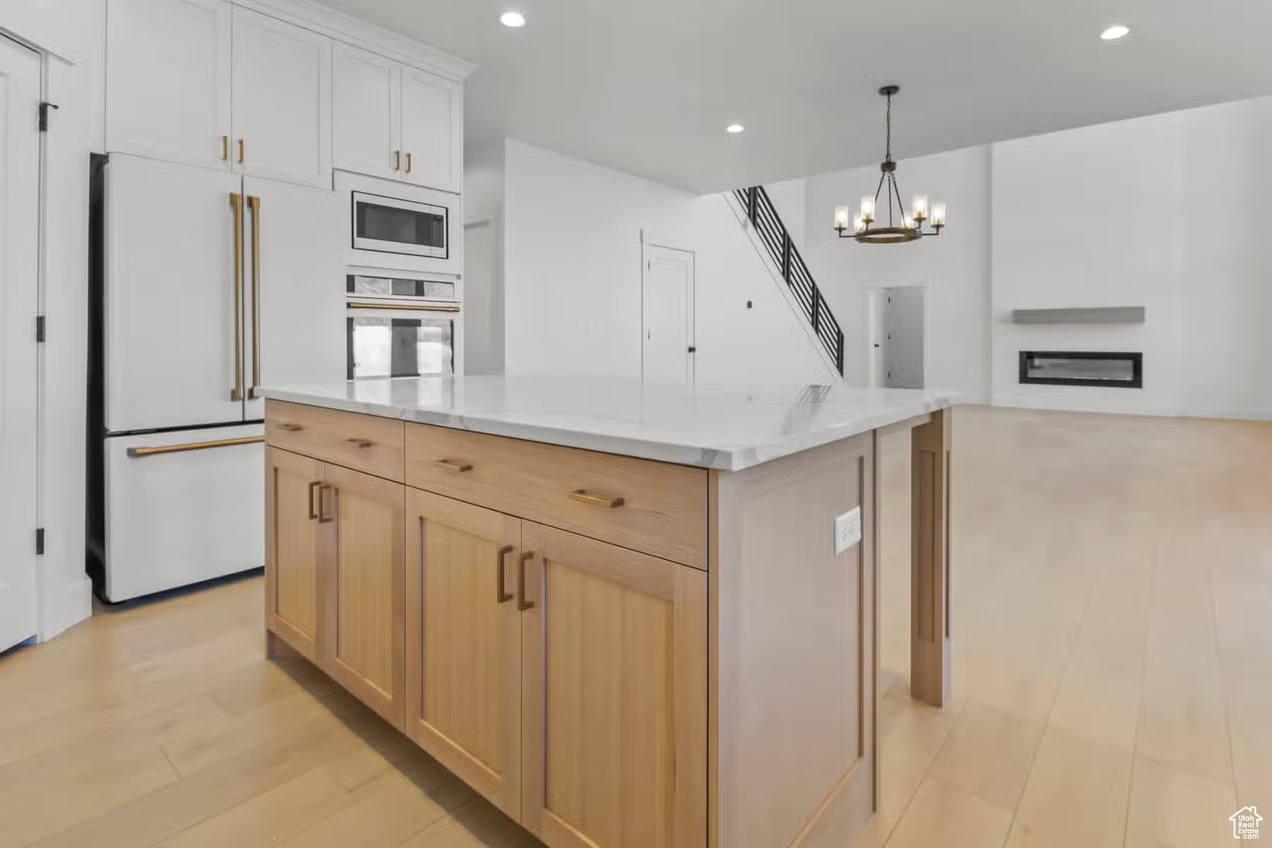 Kitchen featuring light hardwood / wood-style floors, stainless steel microwave, wall oven, white cabinets, and pendant lighting