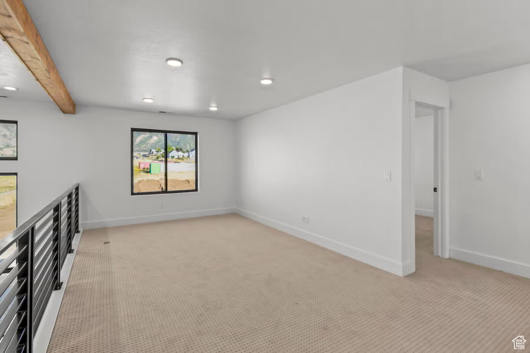 Carpeted spare room with beam ceiling