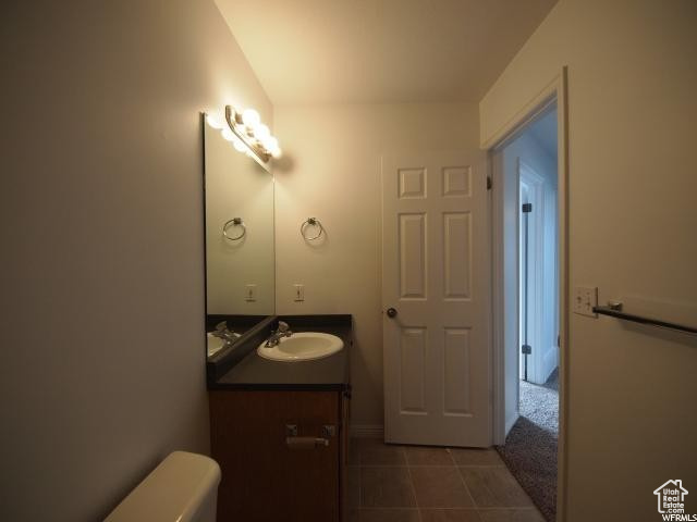 Upstairs full bathroom with toilet, tile flooring, and large vanity