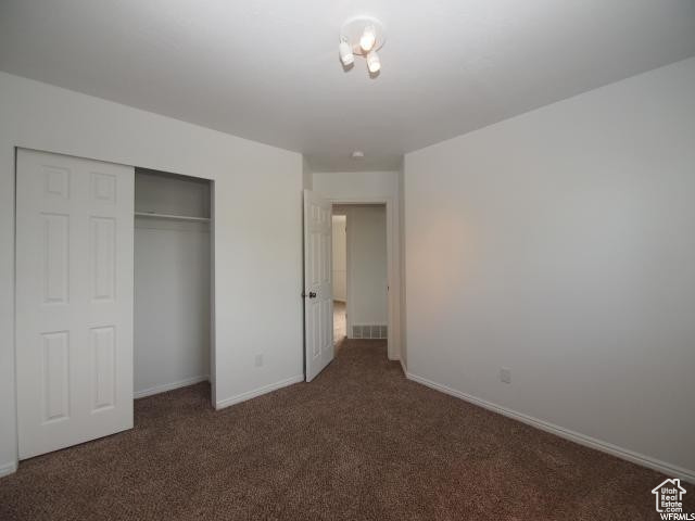 Upstairs bedroom featuring a closet and dark carpet
