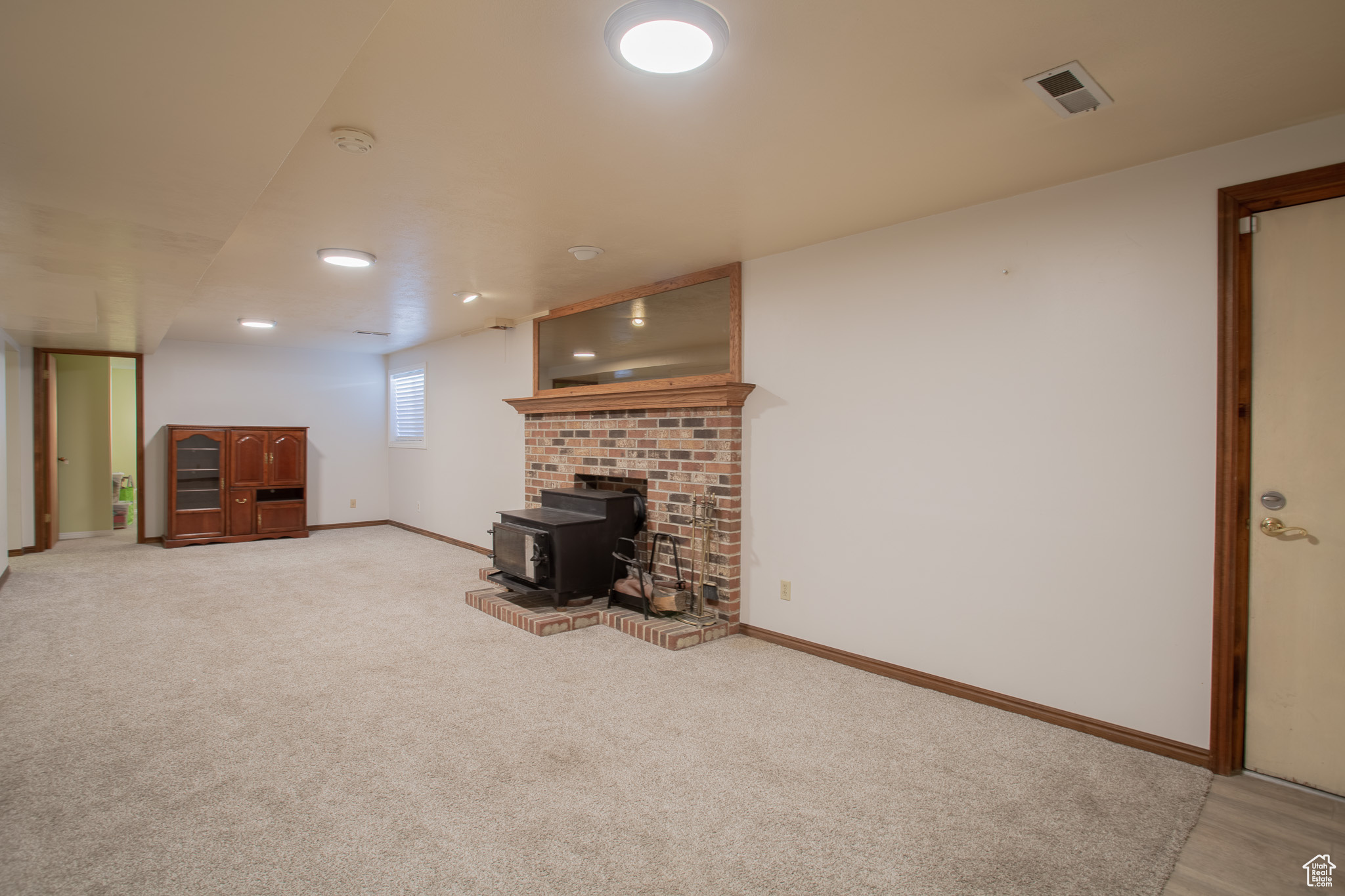 Unfurnished living room featuring light colored carpet, a fireplace, and a wood stove