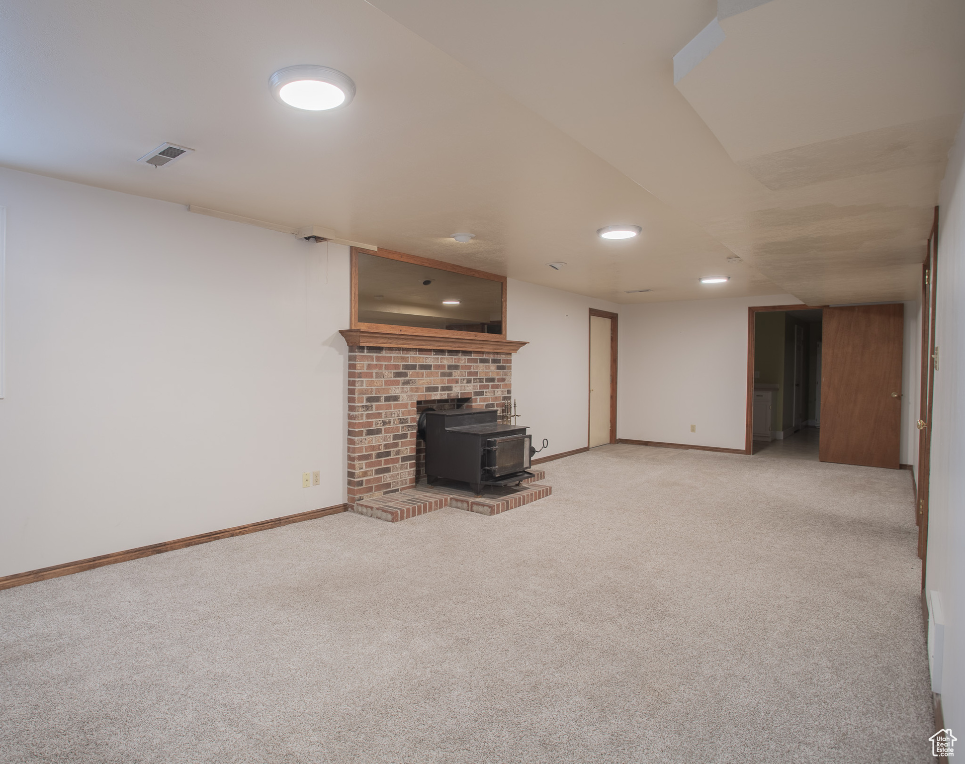 Unfurnished living room with a fireplace, a wood stove, and light carpet