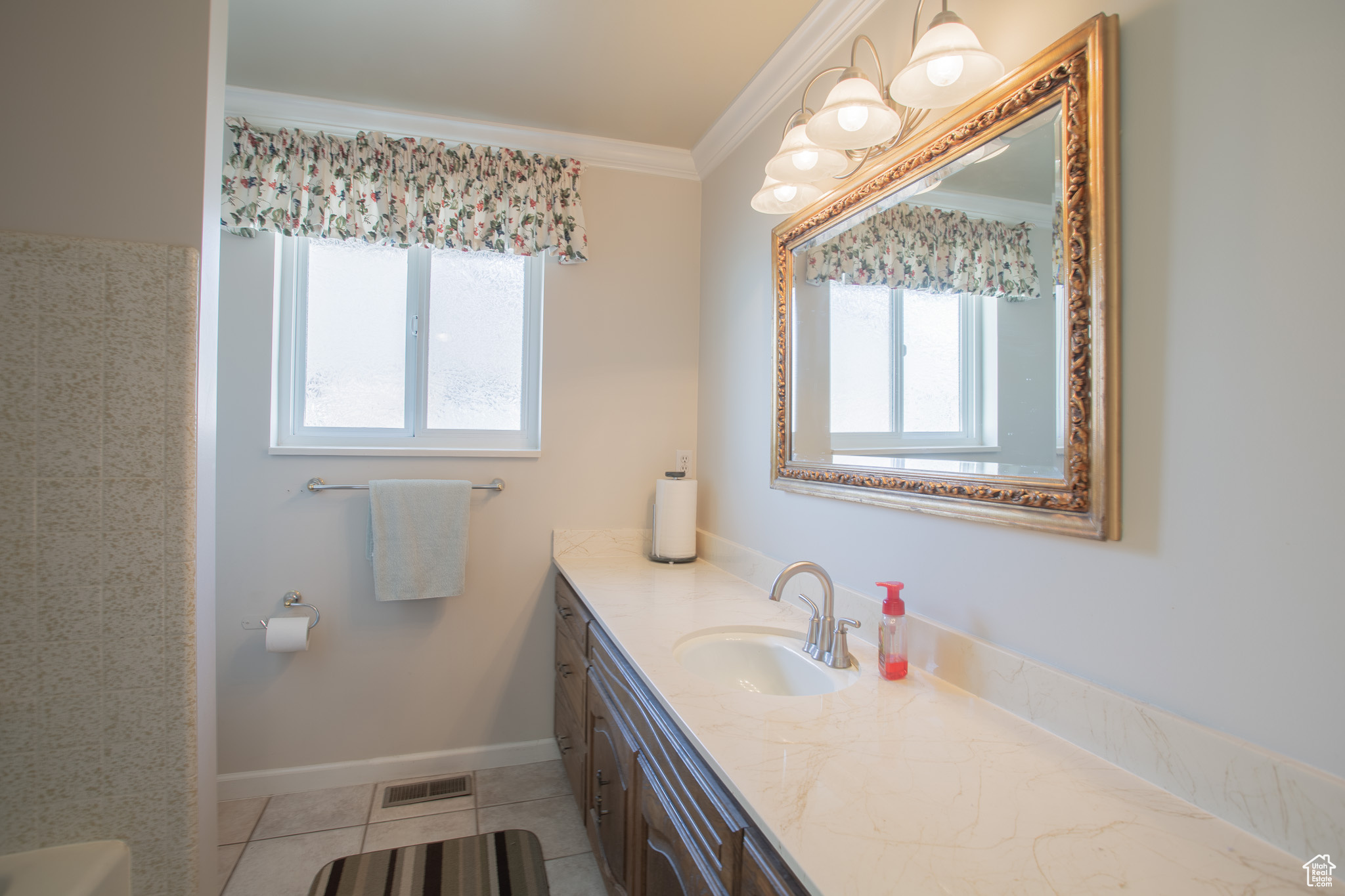 Bathroom with a healthy amount of sunlight, oversized vanity, ornamental molding, and tile flooring
