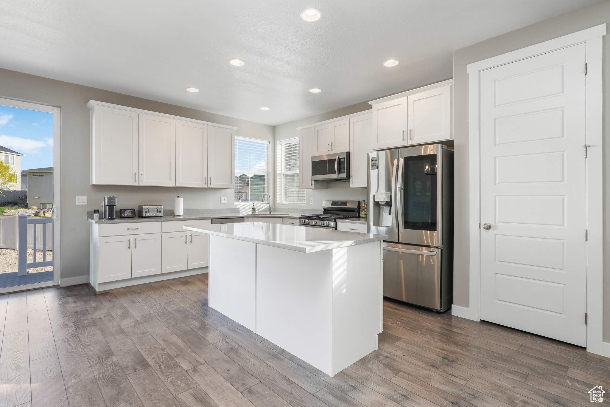 Kitchen featuring a kitchen island, white cabinets, sink, stainless steel appliances, and hardwood / wood-style flooring