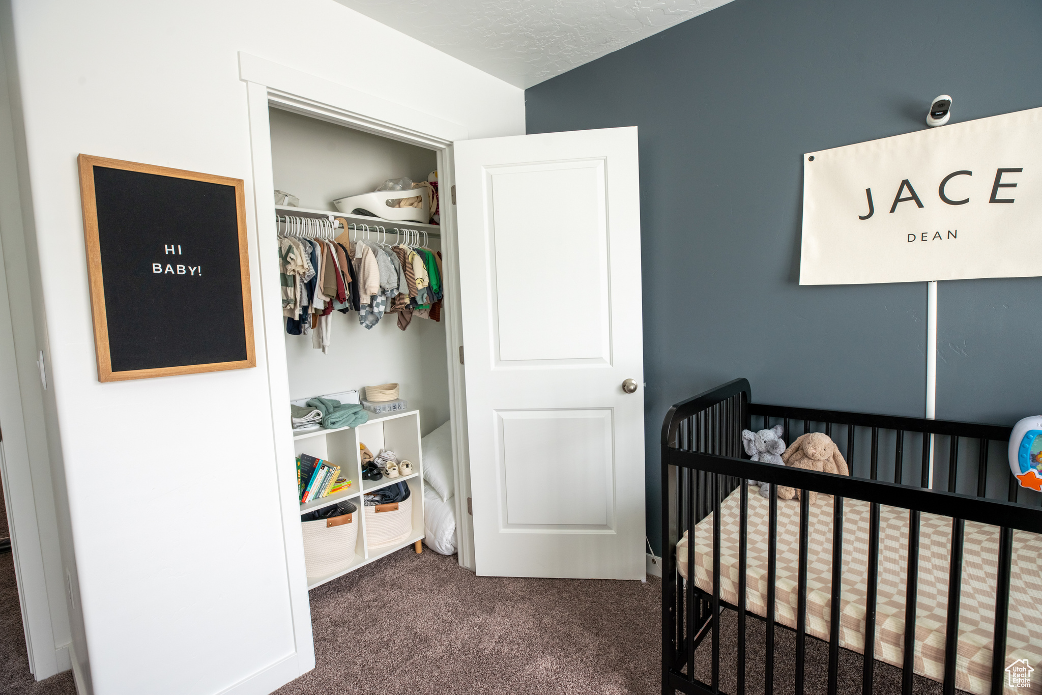 Bedroom featuring a closet, a nursery area, dark carpet, and vaulted ceiling