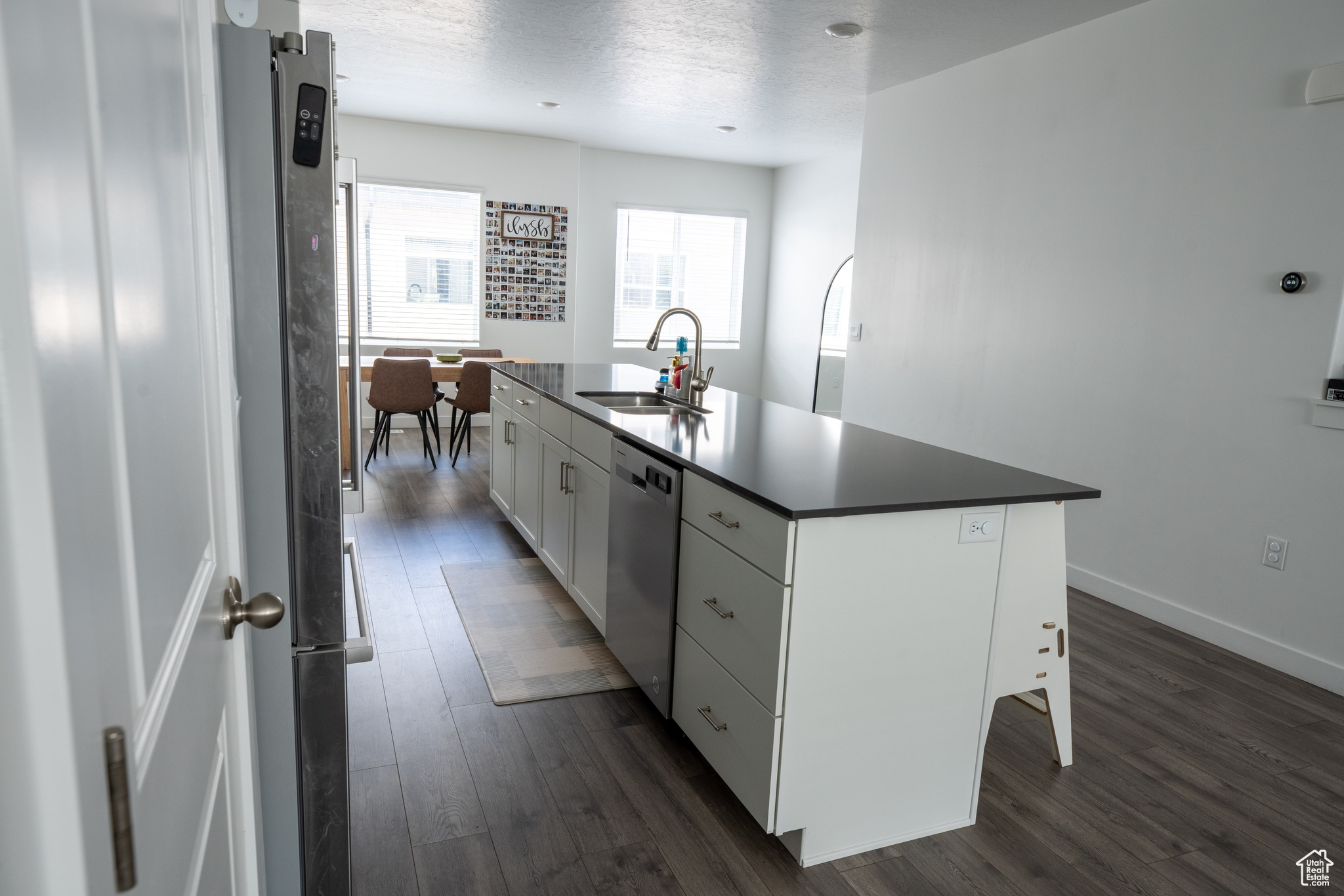 Kitchen featuring sink, dark wood-type flooring, white cabinetry, and a kitchen island with sink