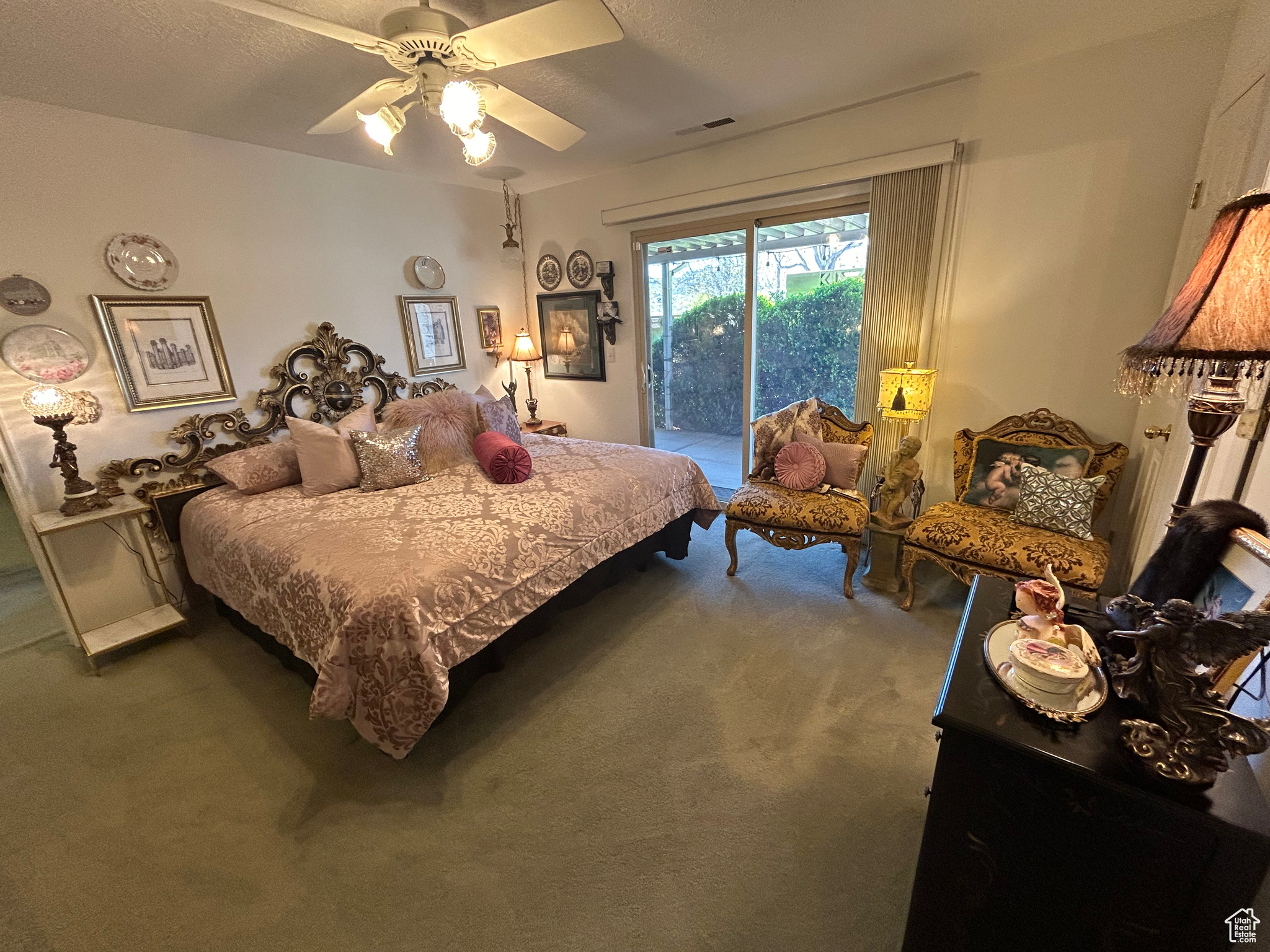 Carpeted bedroom with a textured ceiling, ceiling fan, and access to outside