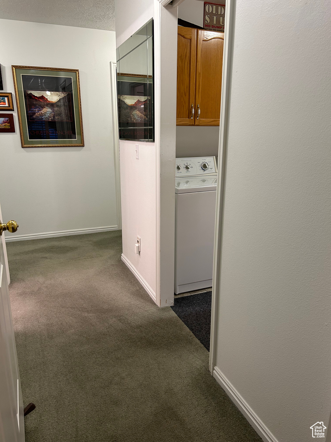 Corridor featuring a textured ceiling, dark carpet, and washer / dryer
