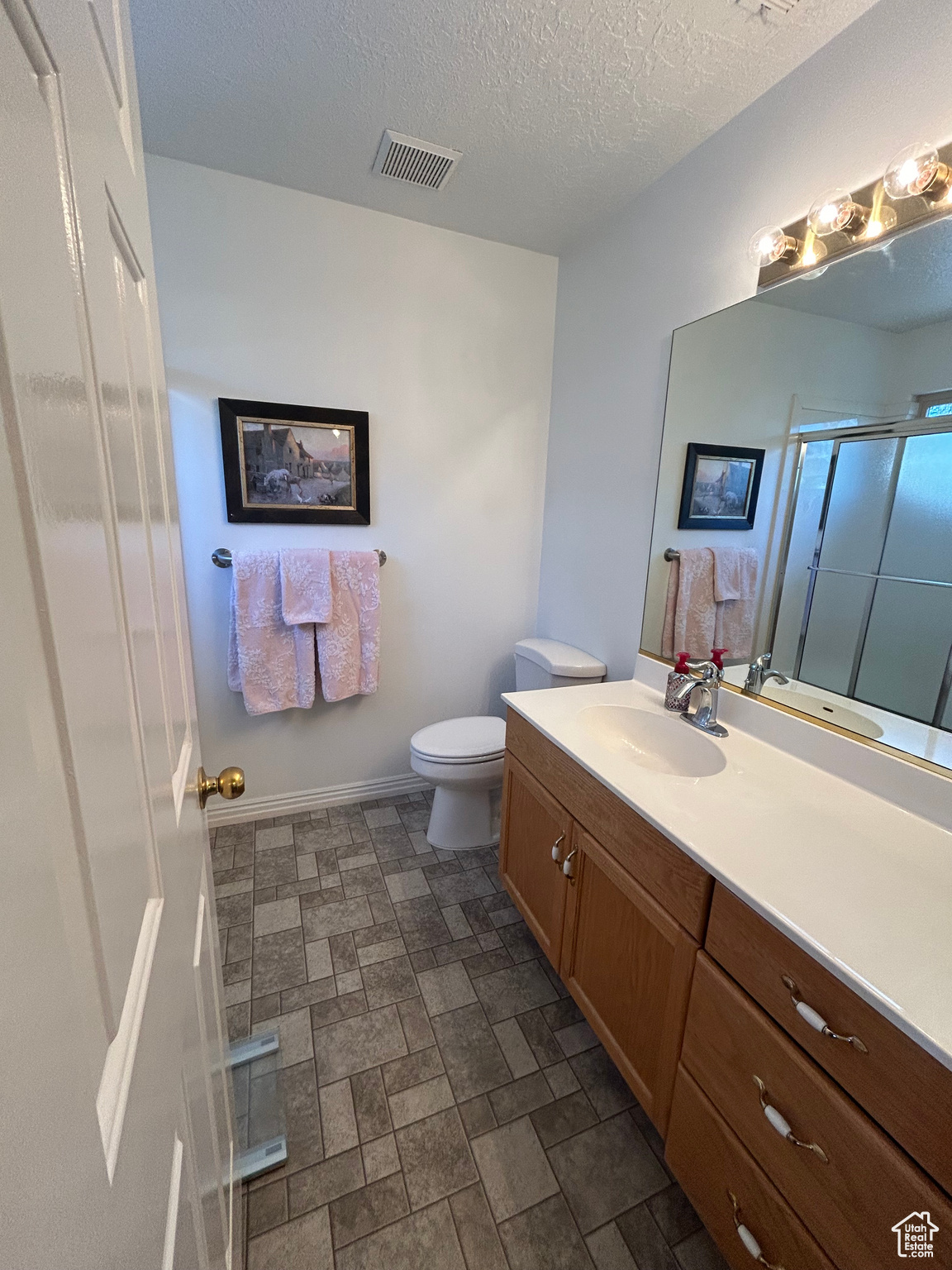 Bathroom featuring tile flooring, oversized vanity, toilet, and a textured ceiling