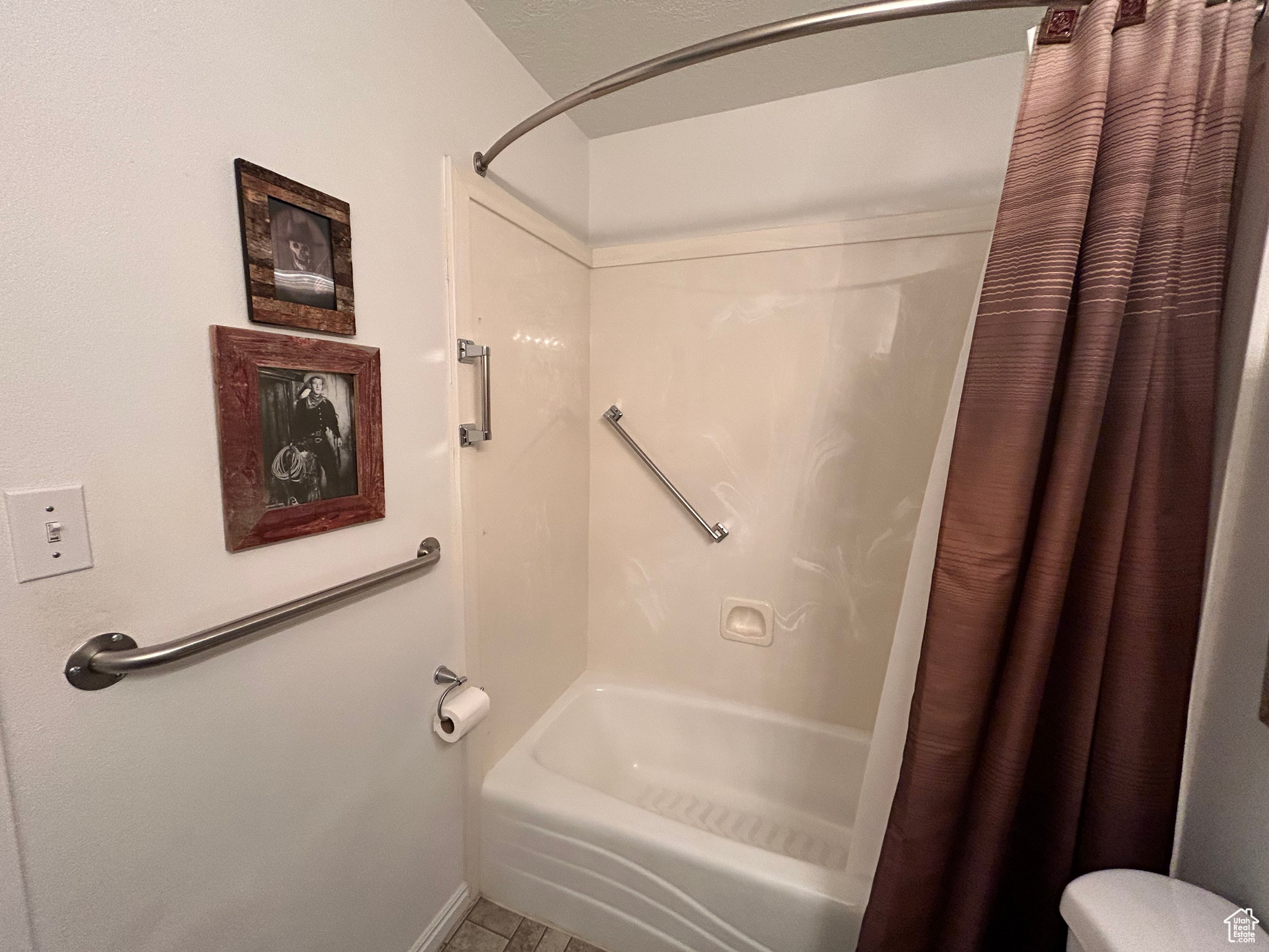 Bathroom featuring tile floors, shower / bath combination with curtain, and toilet