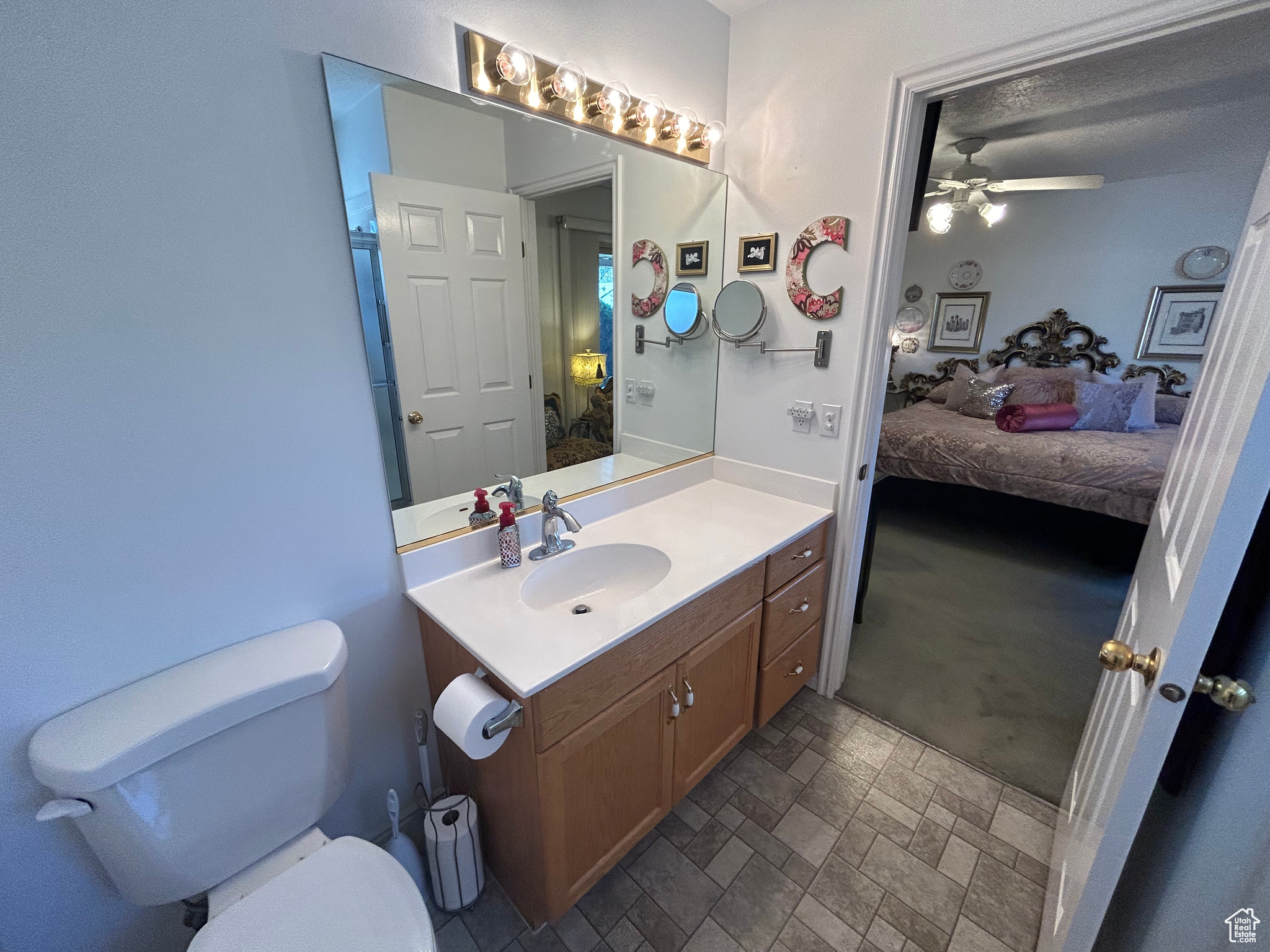 Bathroom featuring vanity with extensive cabinet space, toilet, tile flooring, and ceiling fan