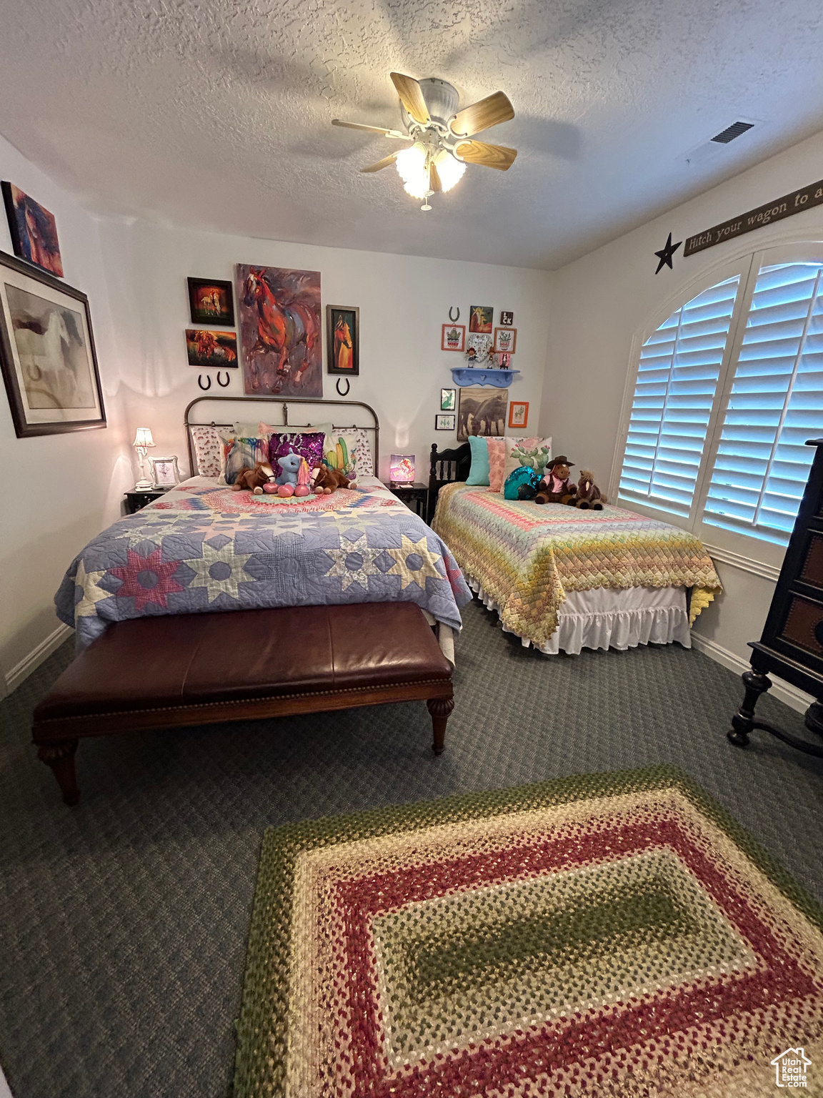 Bedroom with a textured ceiling, carpet floors, and ceiling fan