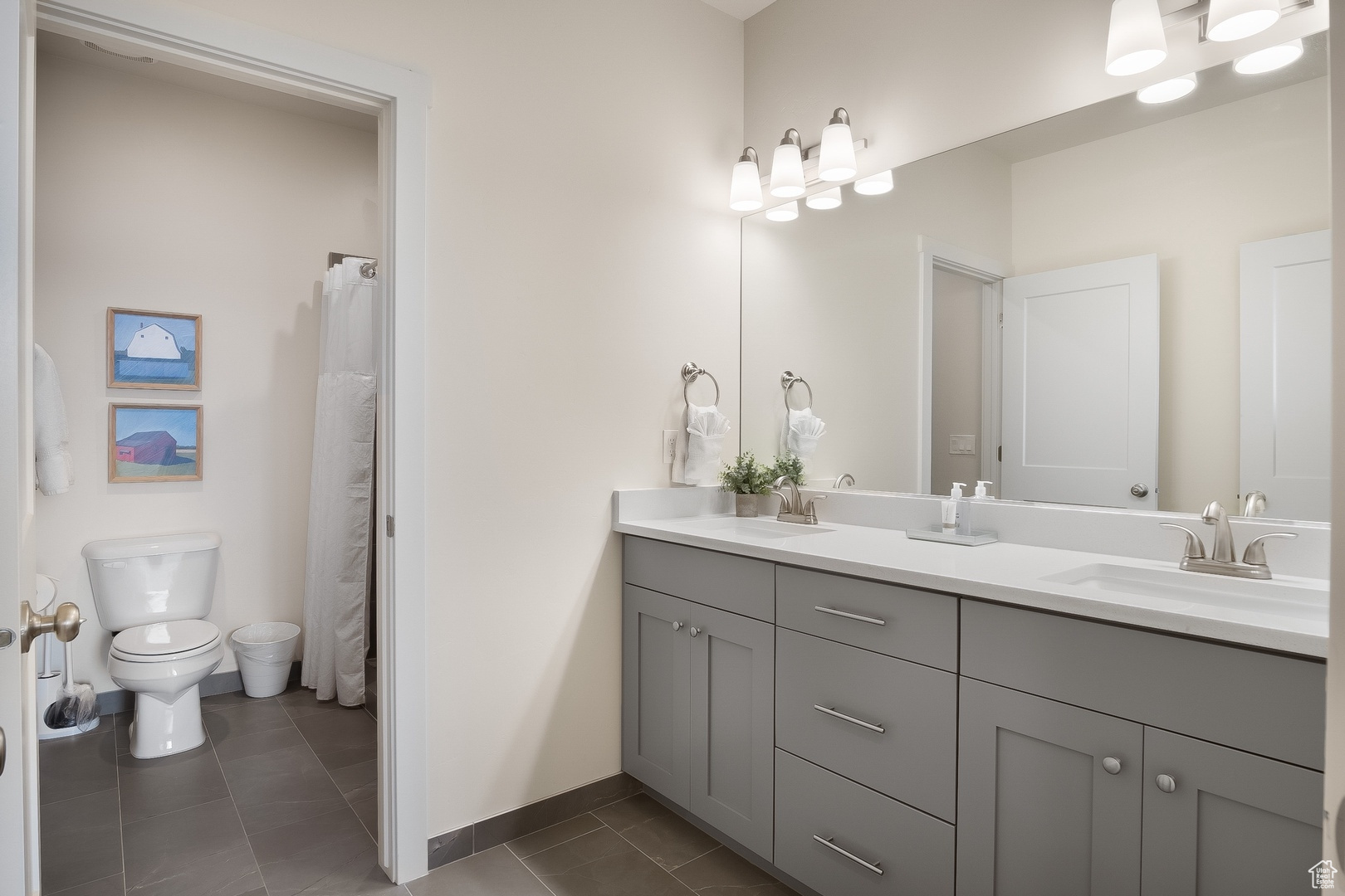 Bathroom featuring tile flooring, double sink vanity, and toilet