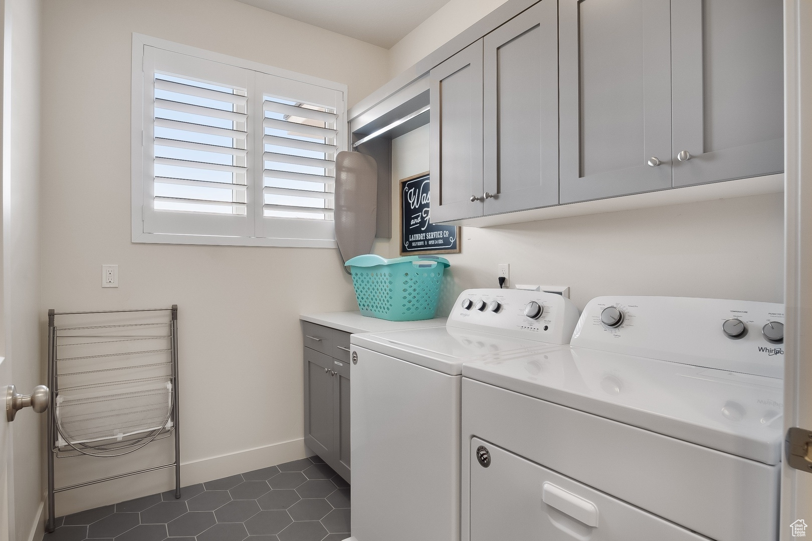 Laundry room featuring dark tile floors, washing machine and clothes dryer, and cabinets