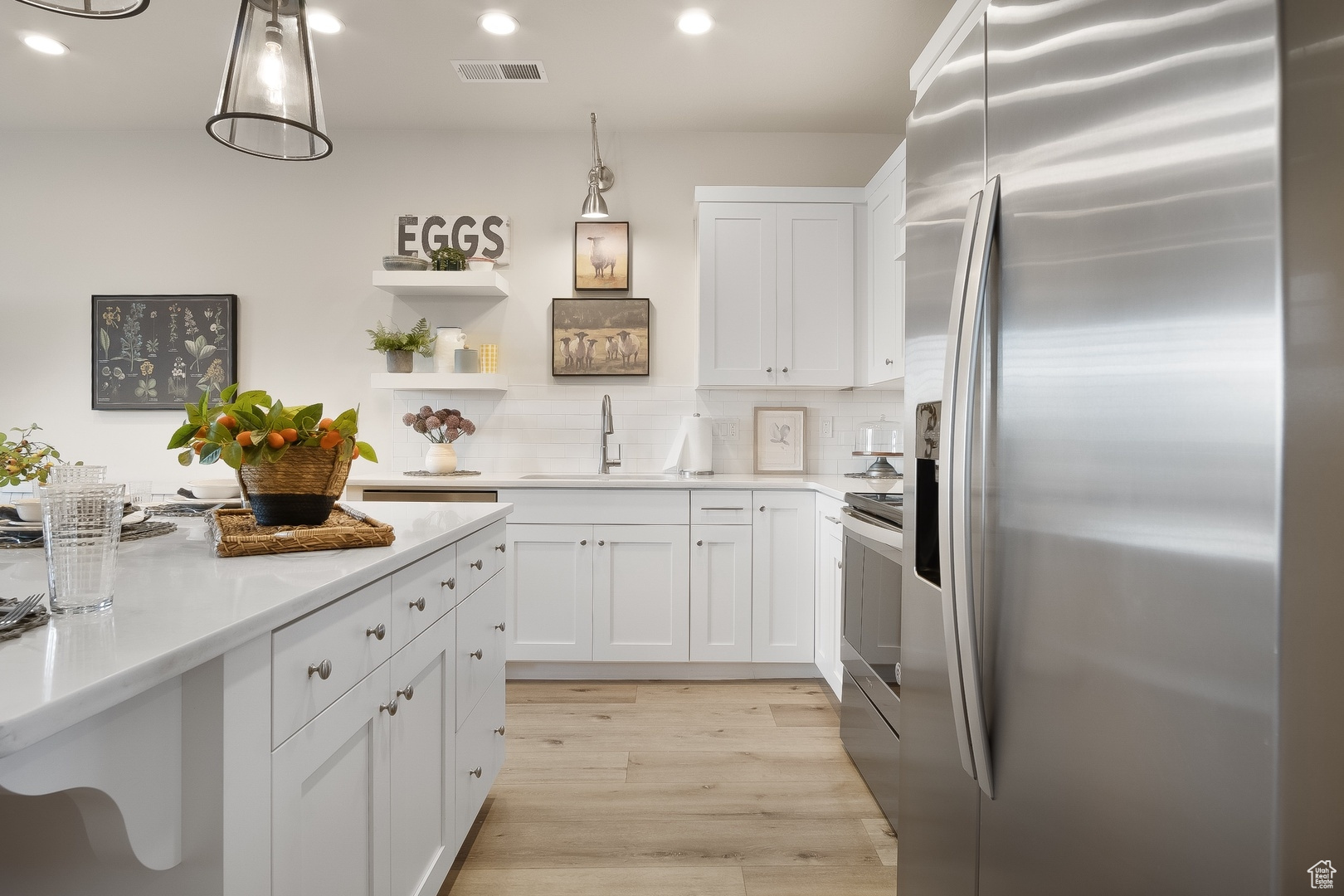 Kitchen with pendant lighting, light hardwood / wood-style flooring, stainless steel appliances, sink, and tasteful backsplash