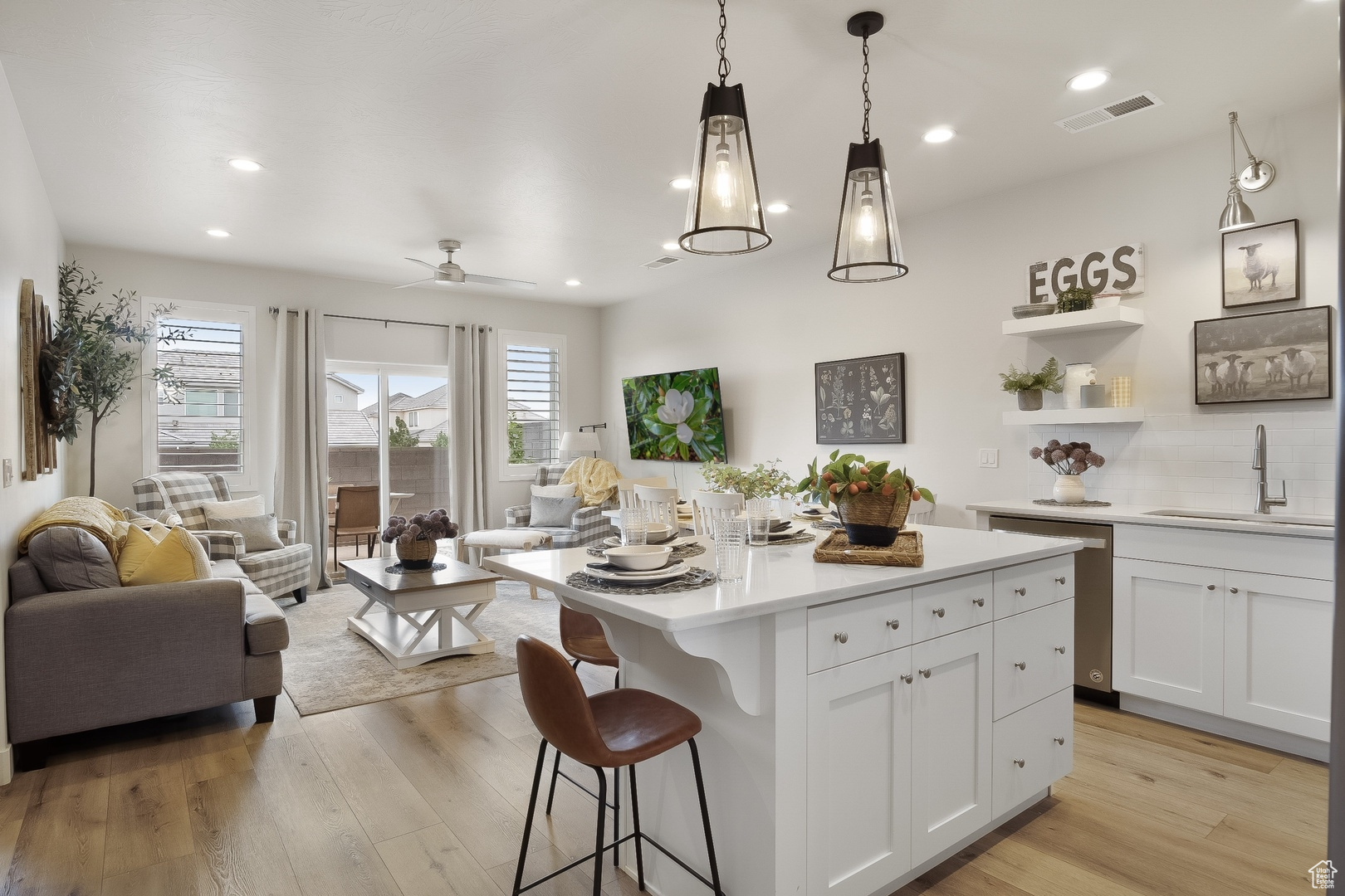 Kitchen featuring light hardwood / wood-style floors, decorative light fixtures, white cabinets, and sink