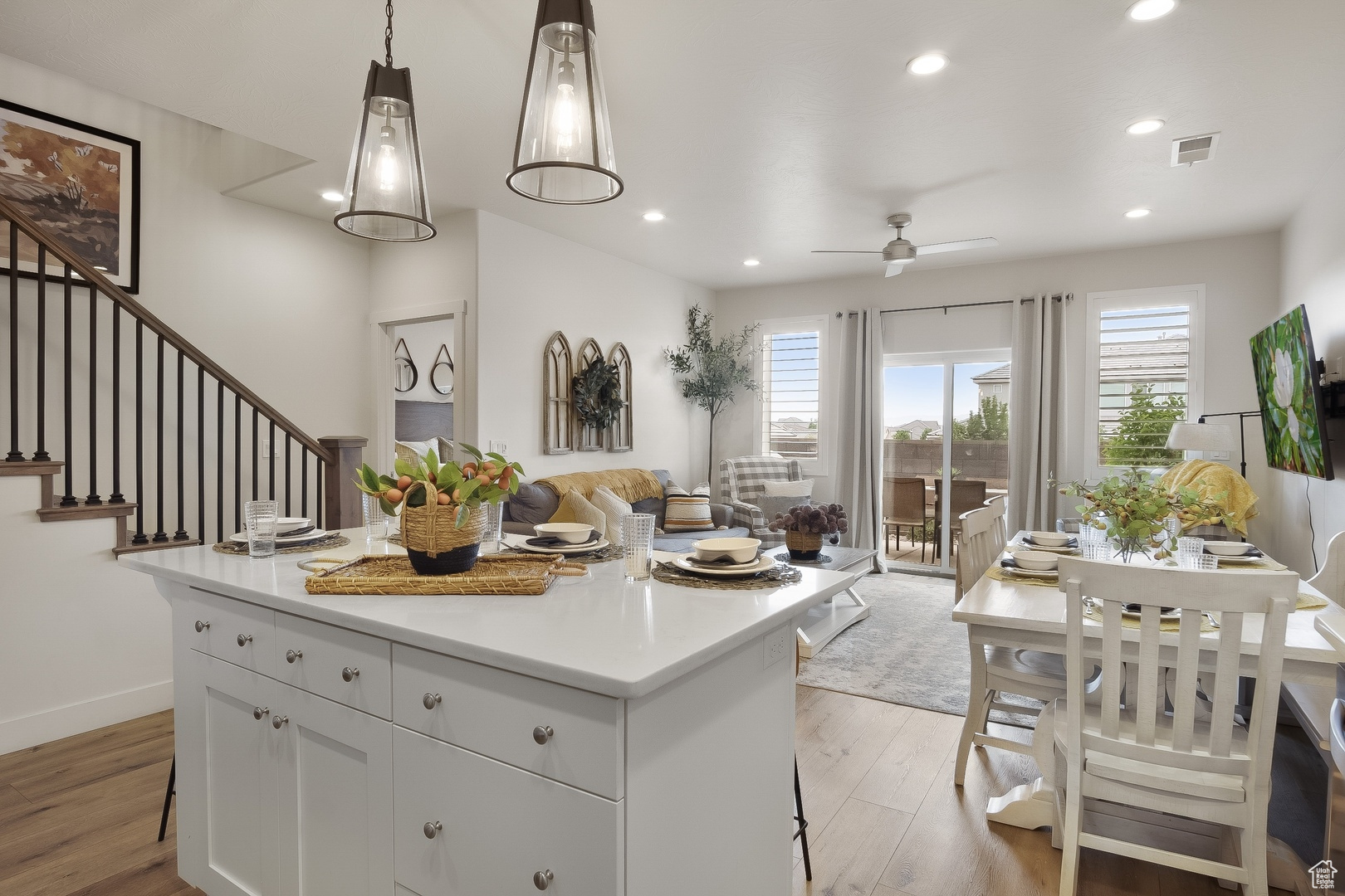 Kitchen featuring a kitchen island, light hardwood / wood-style floors, hanging light fixtures, and white cabinetry