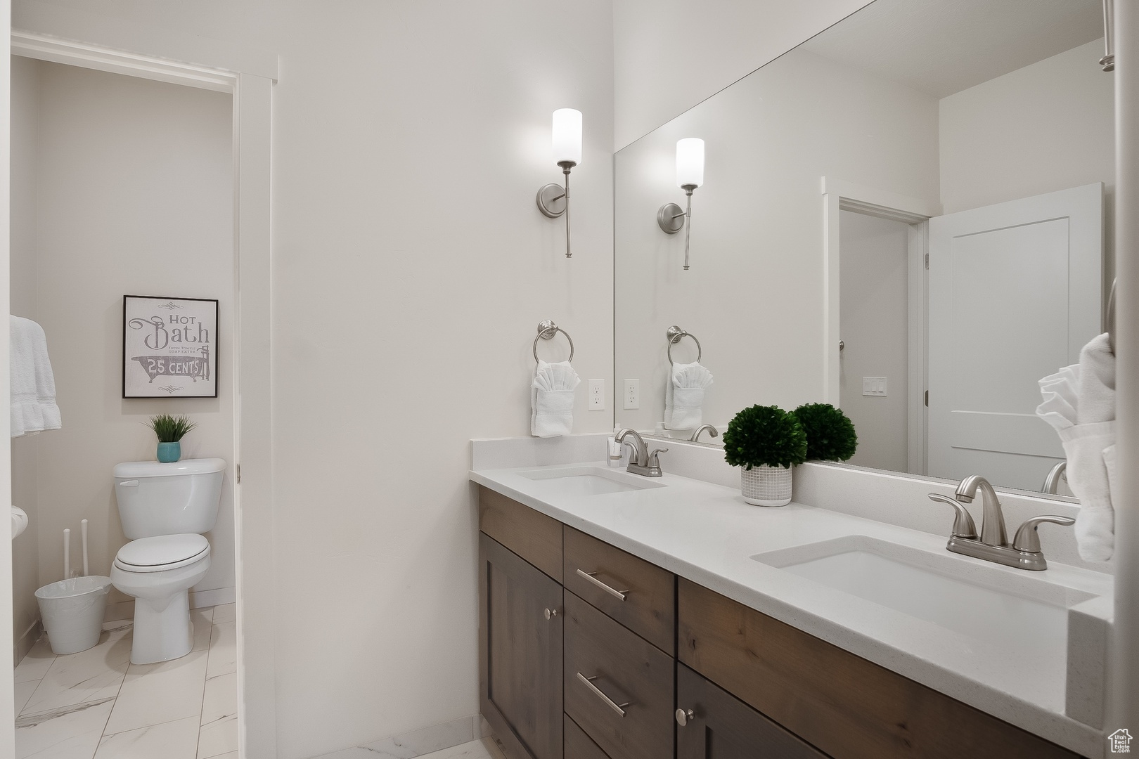 Bathroom with double sink vanity, toilet, and tile floors