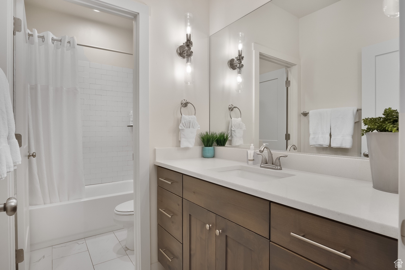 Full bathroom featuring tile flooring, toilet, large vanity, and shower / bathtub combination with curtain