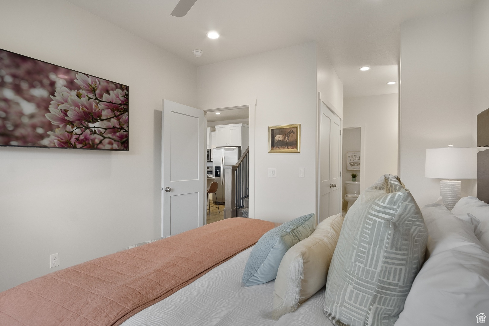 Bedroom featuring connected bathroom, ceiling fan, stainless steel fridge, and a closet