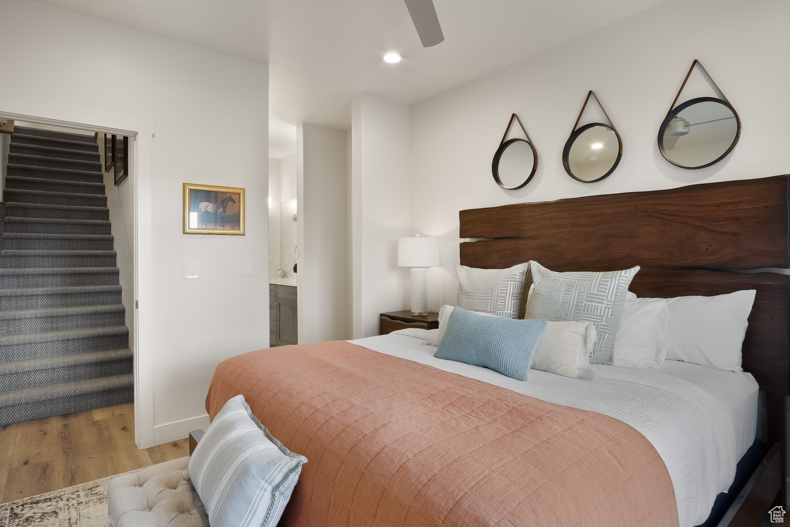 Bedroom with ensuite bath, light hardwood / wood-style flooring, and ceiling fan