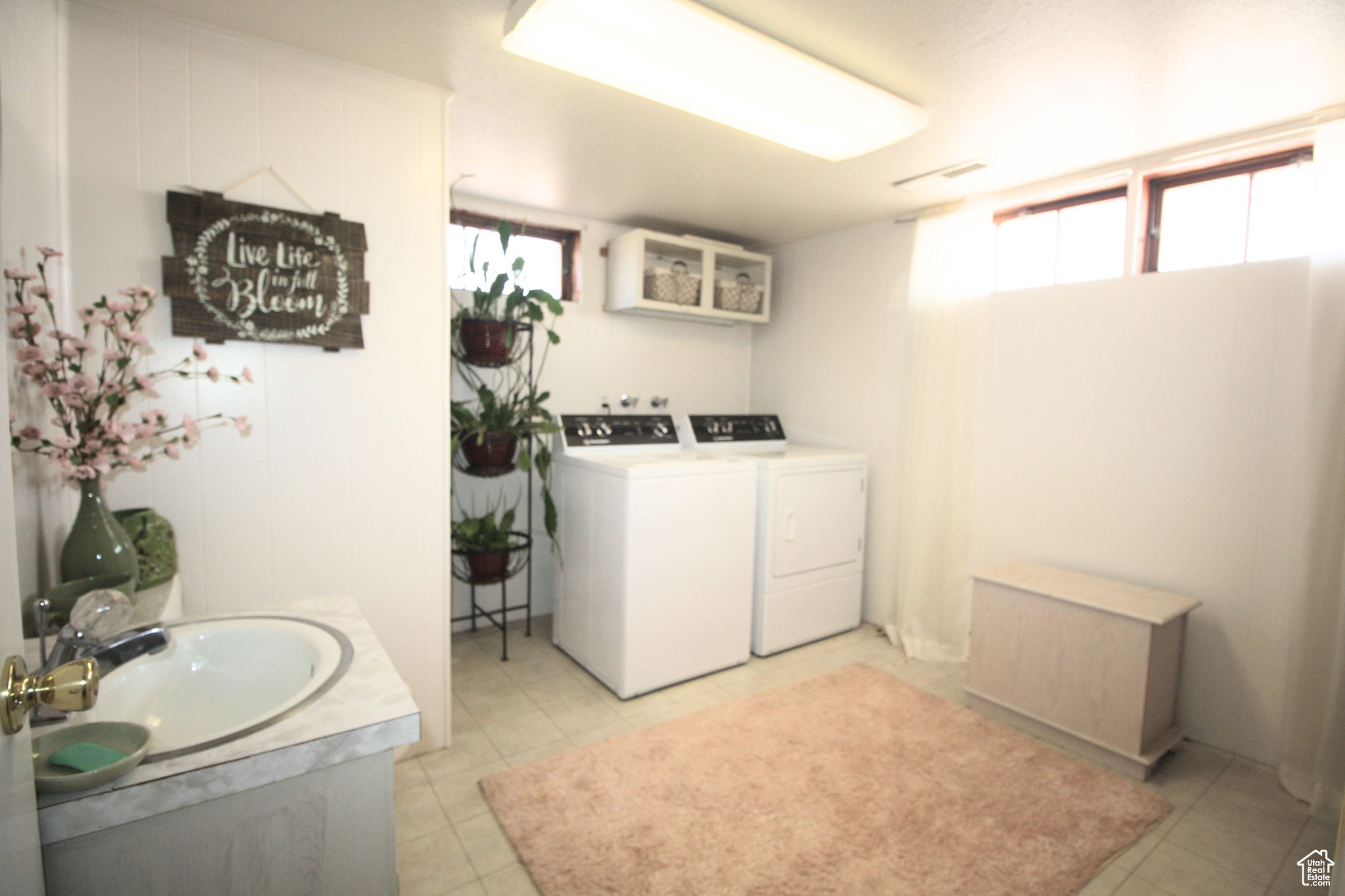 Clothes washing area featuring sink, light tile floors, washer and dryer, and plenty of natural light