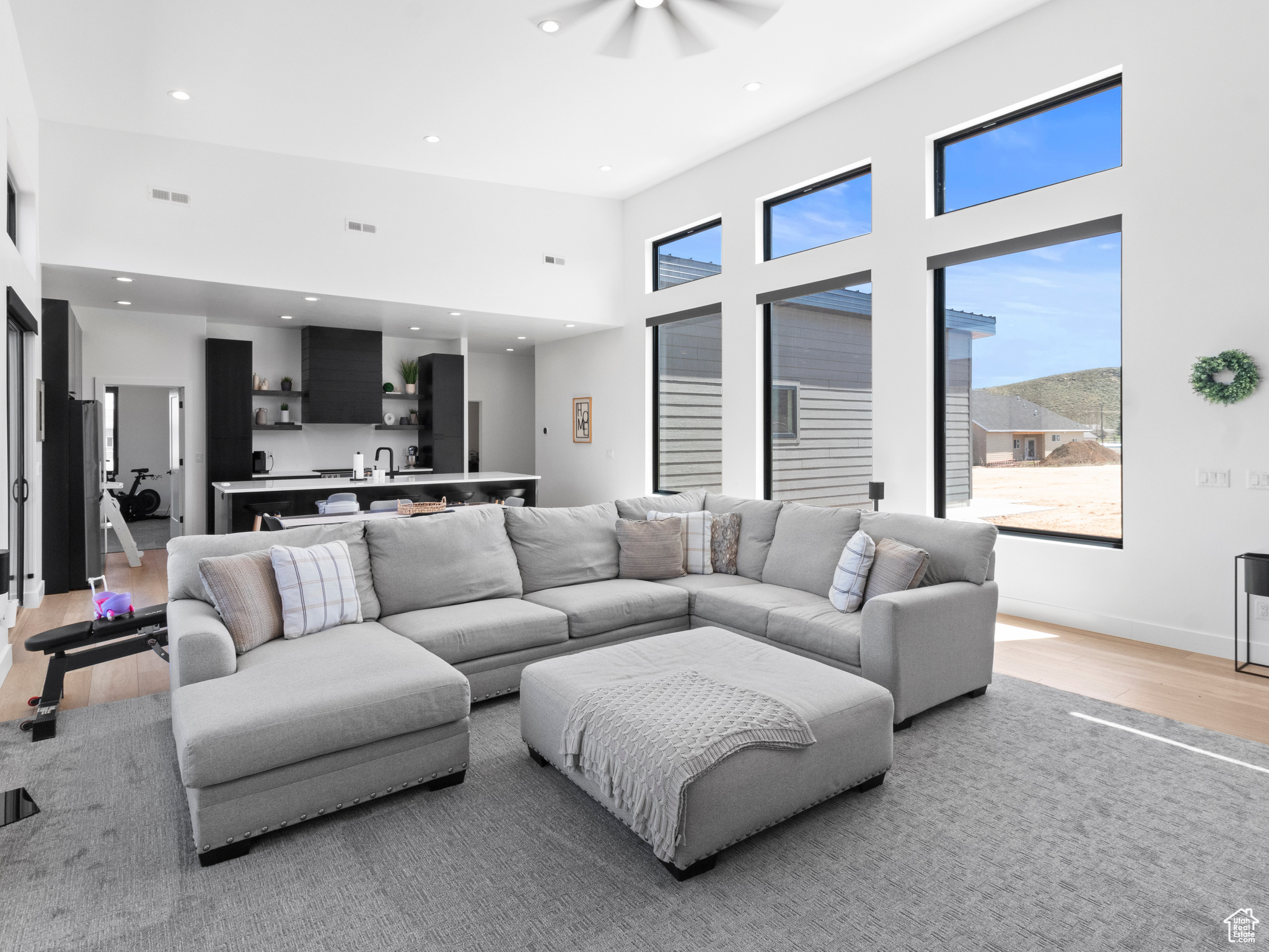 Living room with ceiling fan, light hardwood / wood-style floors, and a high ceiling