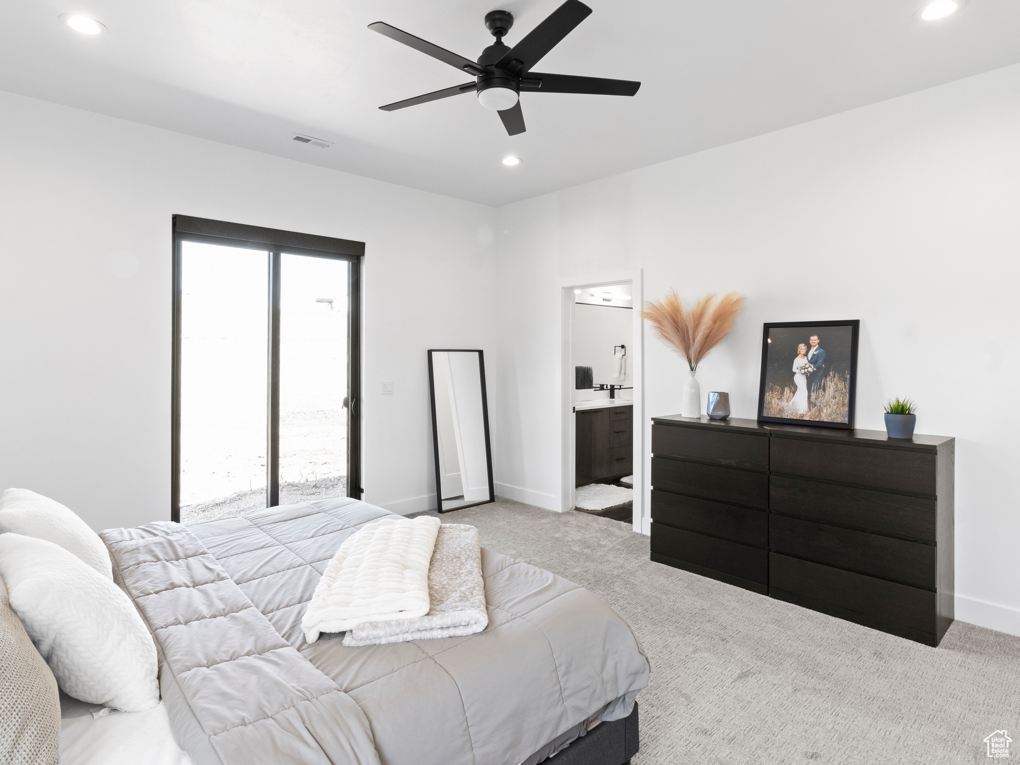 Bedroom featuring multiple windows, light carpet, ceiling fan, and ensuite bathroom