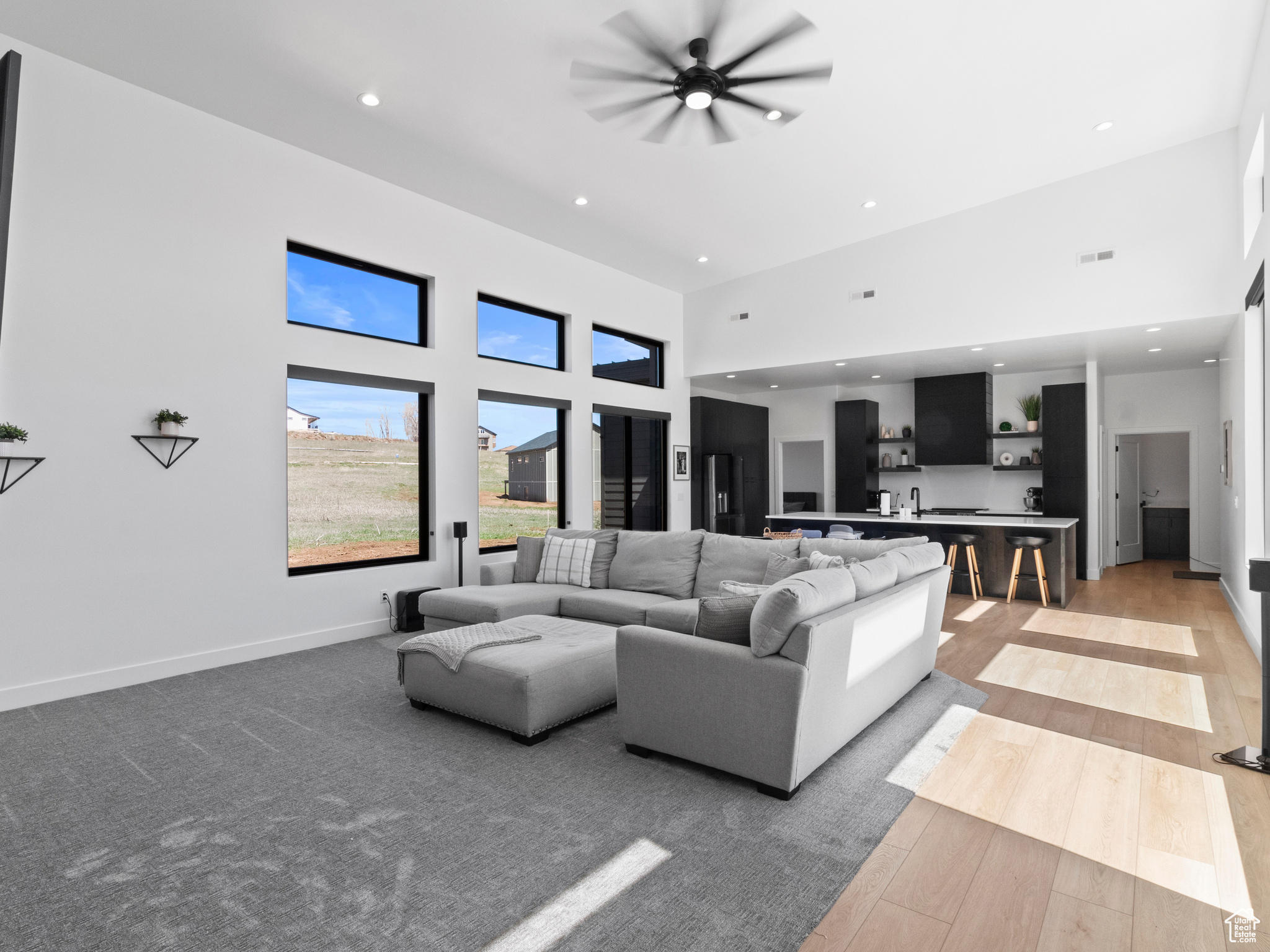 Living room featuring a high ceiling, ceiling fan, and light wood-type flooring