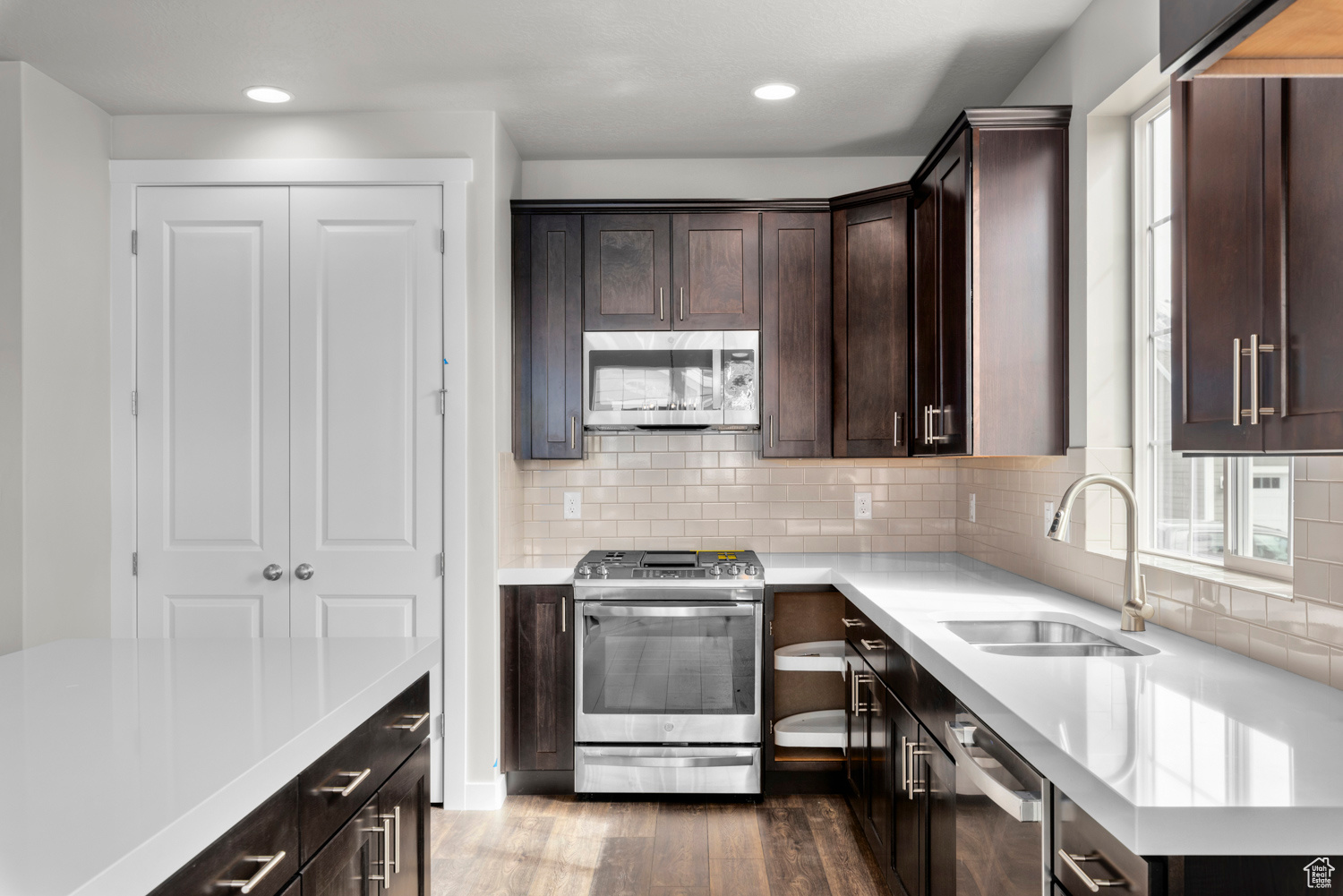 Kitchen featuring appliances with stainless steel finishes, sink, tasteful backsplash, dark wood-type flooring, and dark brown cabinets