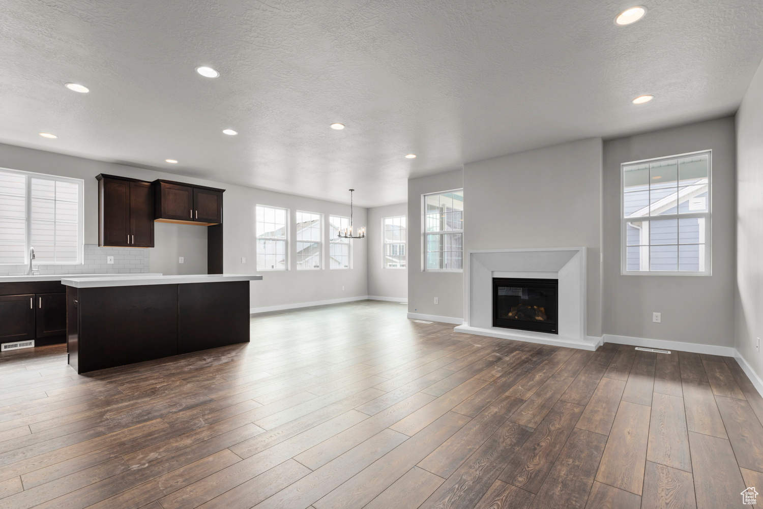 Kitchen featuring dark brown cabinets, tasteful backsplash, hardwood / wood-style flooring, sink, and a center island