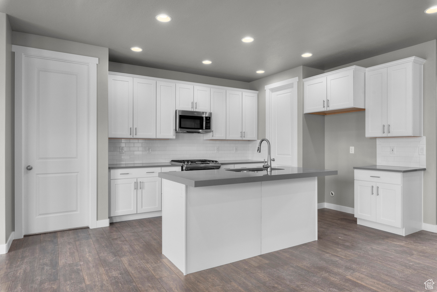 Kitchen featuring dark hardwood / wood-style flooring, appliances with stainless steel finishes, and white cabinetry
