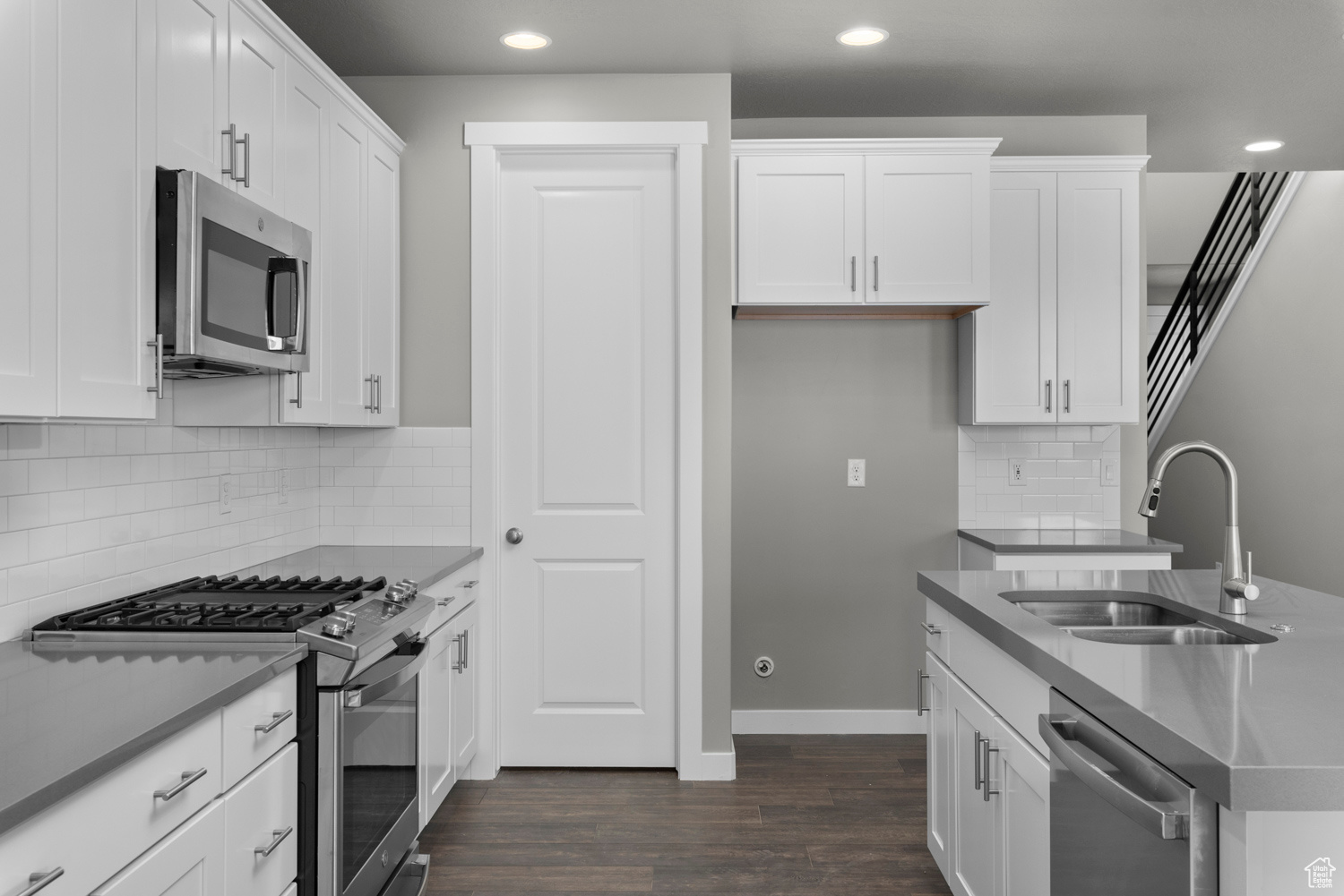 Kitchen with stainless steel appliances, dark hardwood / wood-style floors, tasteful backsplash, white cabinetry, and sink