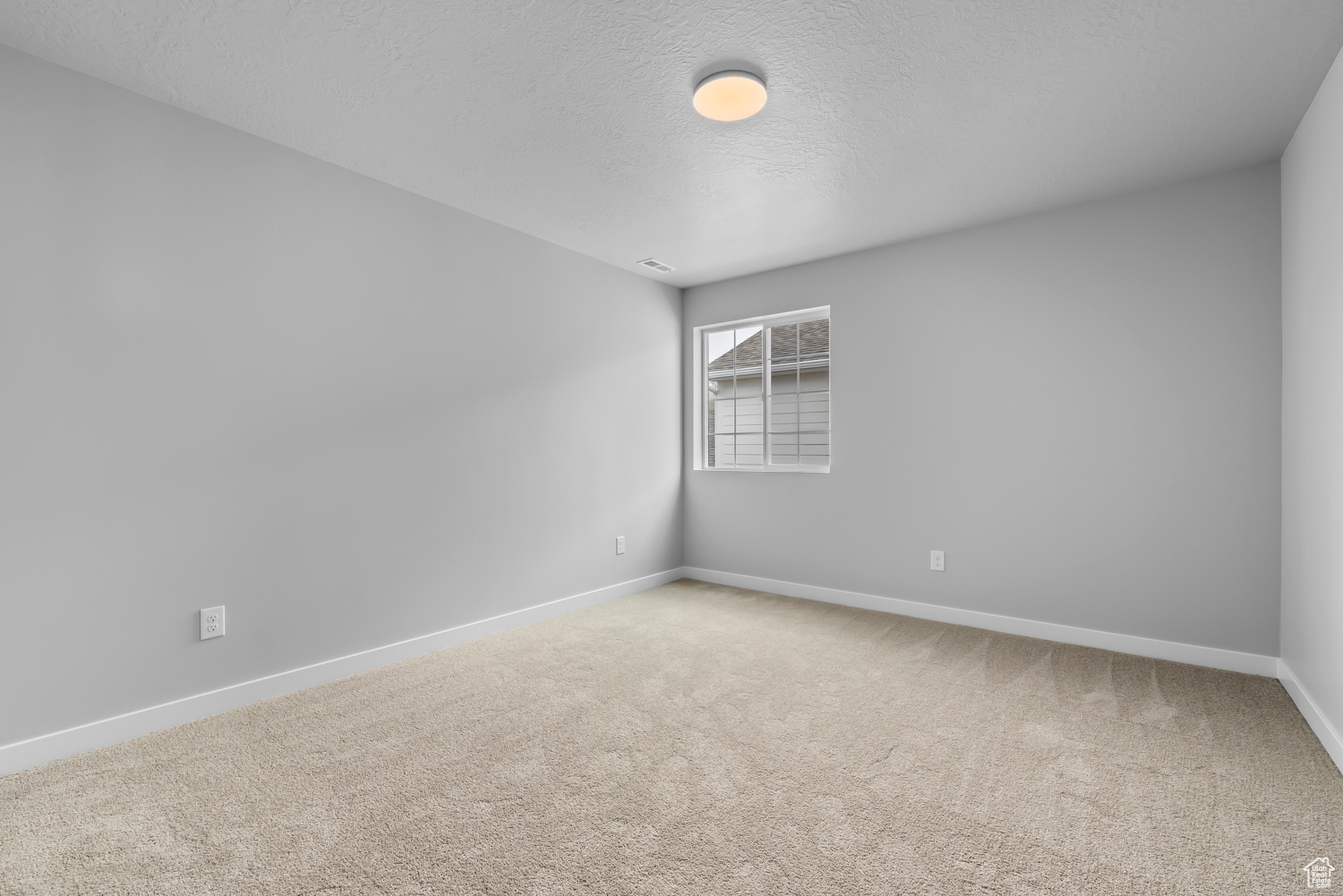 Unfurnished room with light colored carpet and a textured ceiling