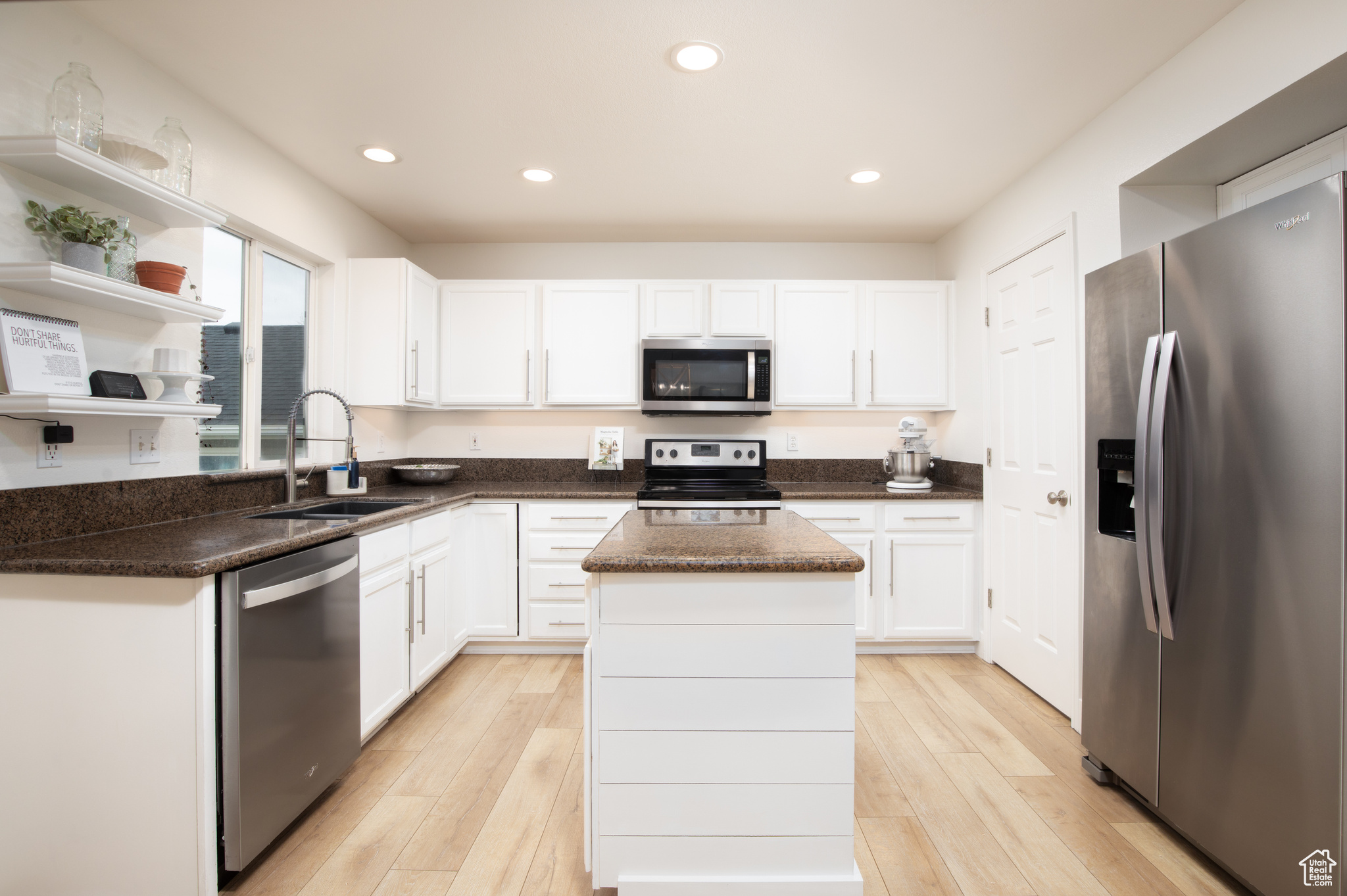 Kitchen with appliances with stainless steel finishes, sink, a kitchen island, and white cabinets